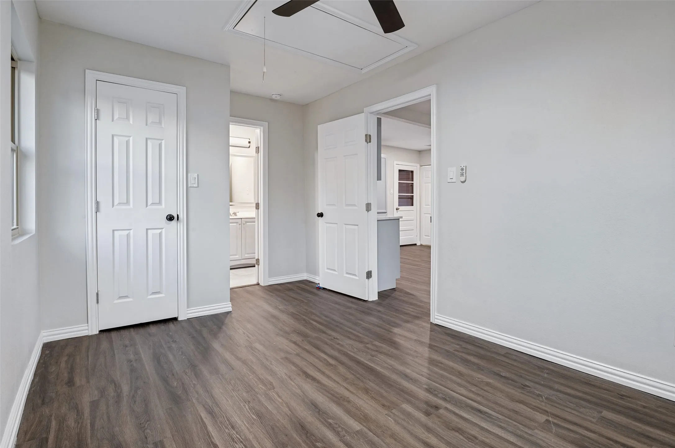 Wood-finish flooring, white paneled doors, and a ceiling fan