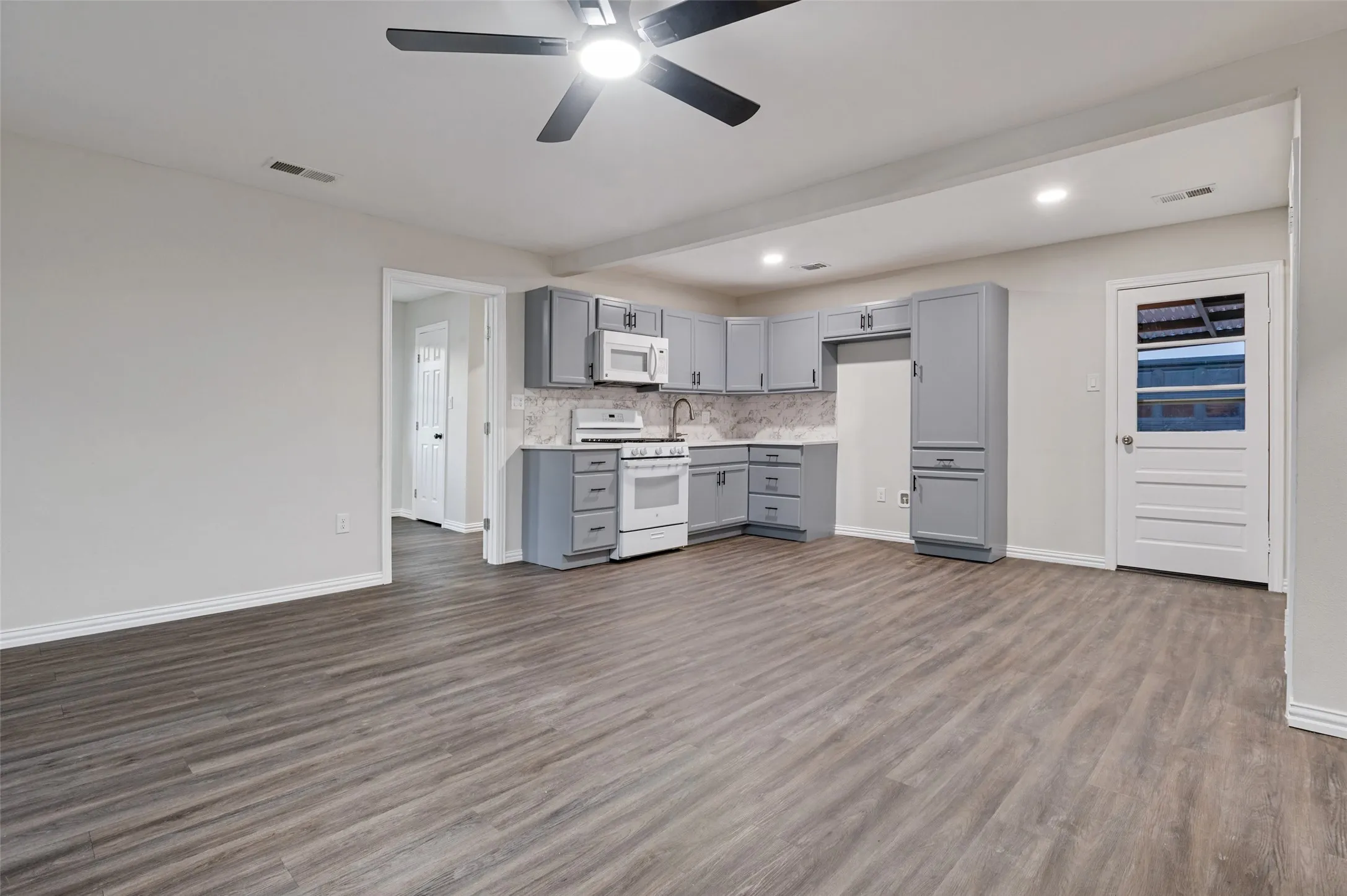 Open-concept living area featuring wood-finish flooring, recessed lighting, and a ceiling fan