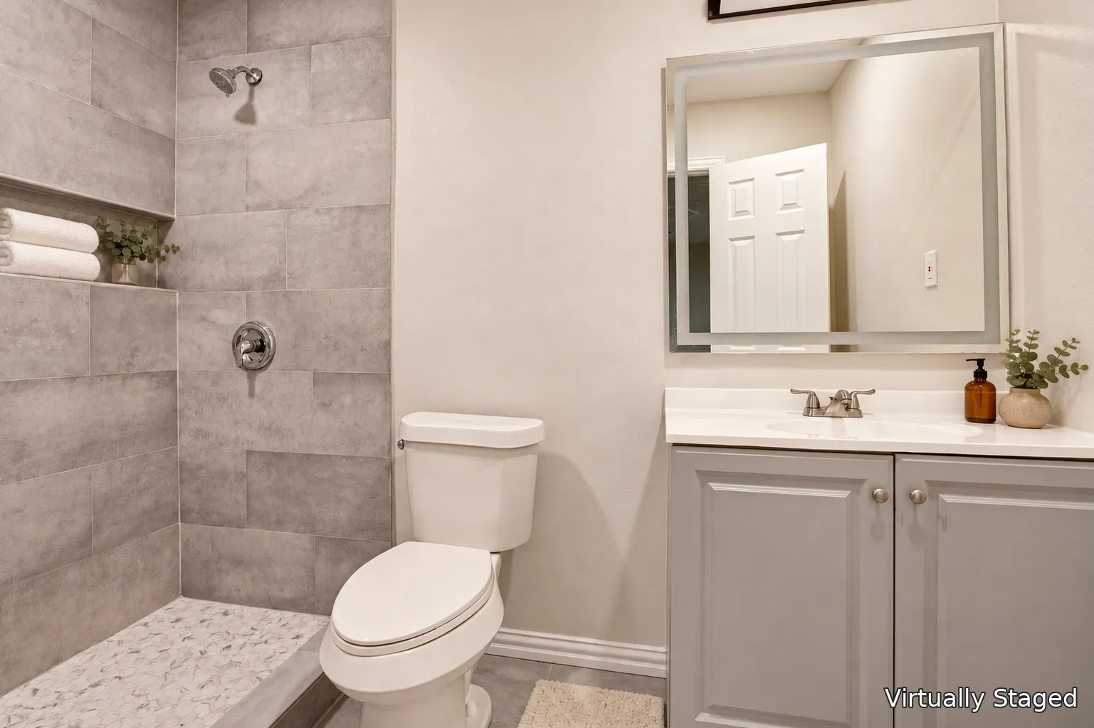 Tiled shower with a built-in niche, pebble-style shower floor, and a chrome shower fixture