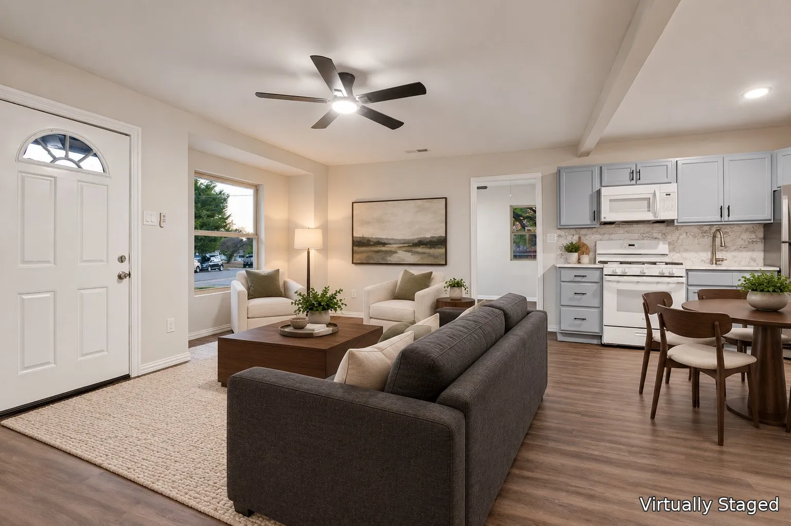 Open-concept living space featuring wood-finish flooring, a ceiling fan, and a kitchen with light blue cabinetry, white appliances, and a tiled backsplash