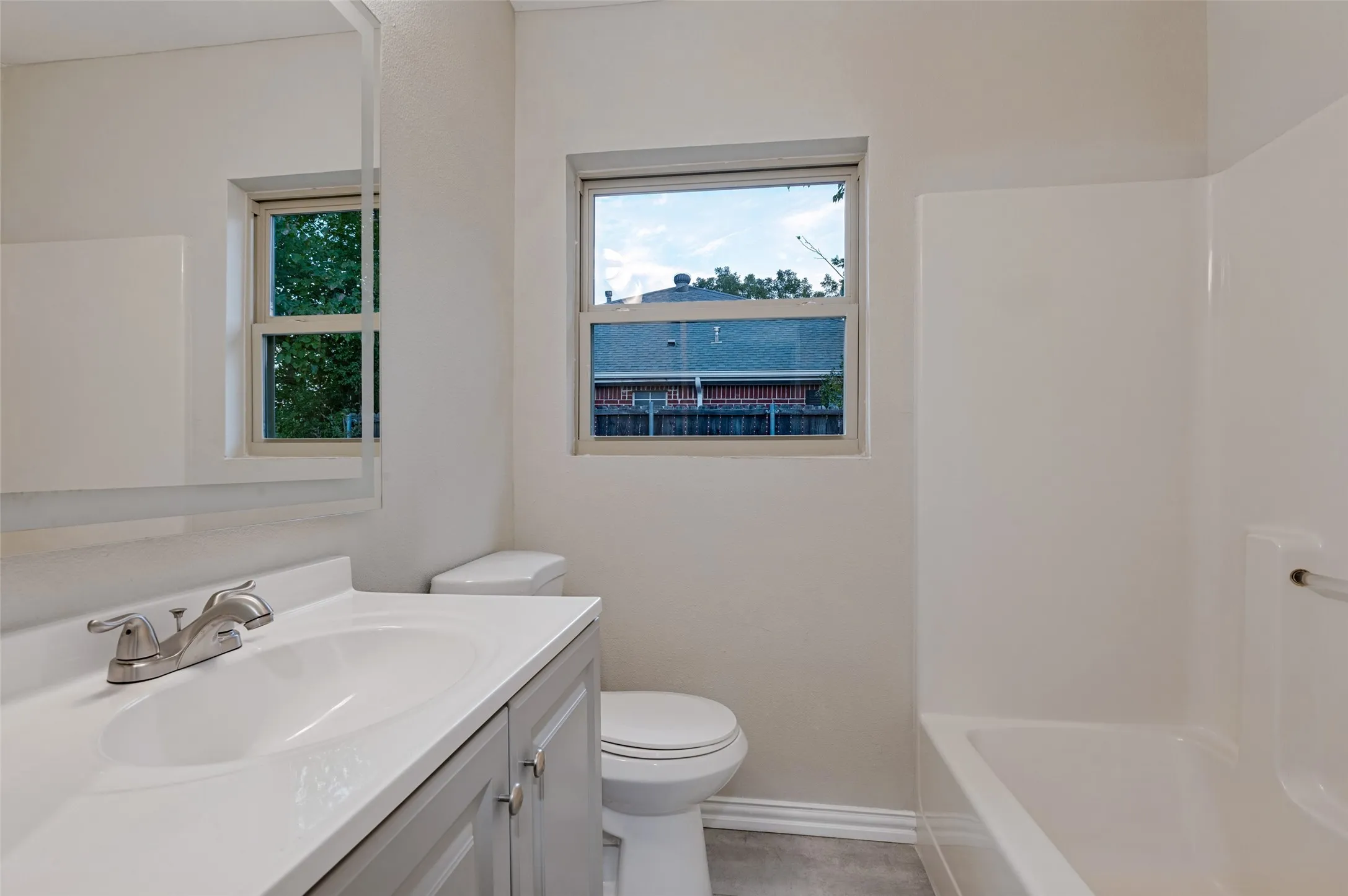 Bathroom featuring a single vanity with light-colored cabinetry, an integrated sink, and a chrome-finish faucet