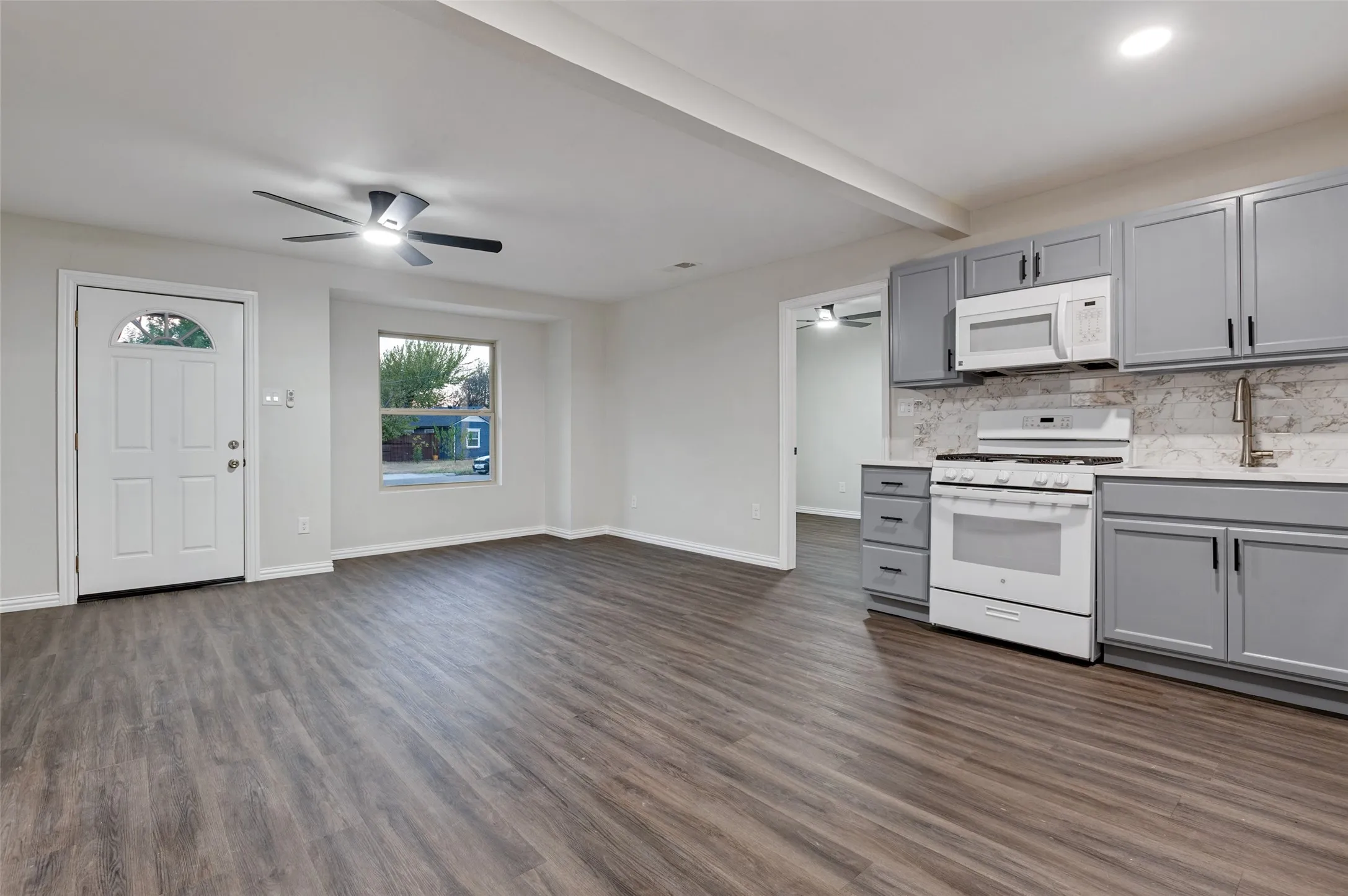 Open-concept living space with wood-finish flooring, recessed lighting, and a ceiling fan