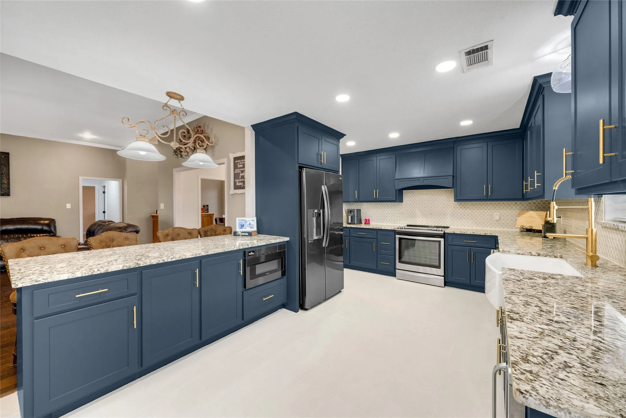 Kitchen featuring blue cabinetry, light granite countertops, stainless steel appliances, a white farmhouse sink, and recessed lighting