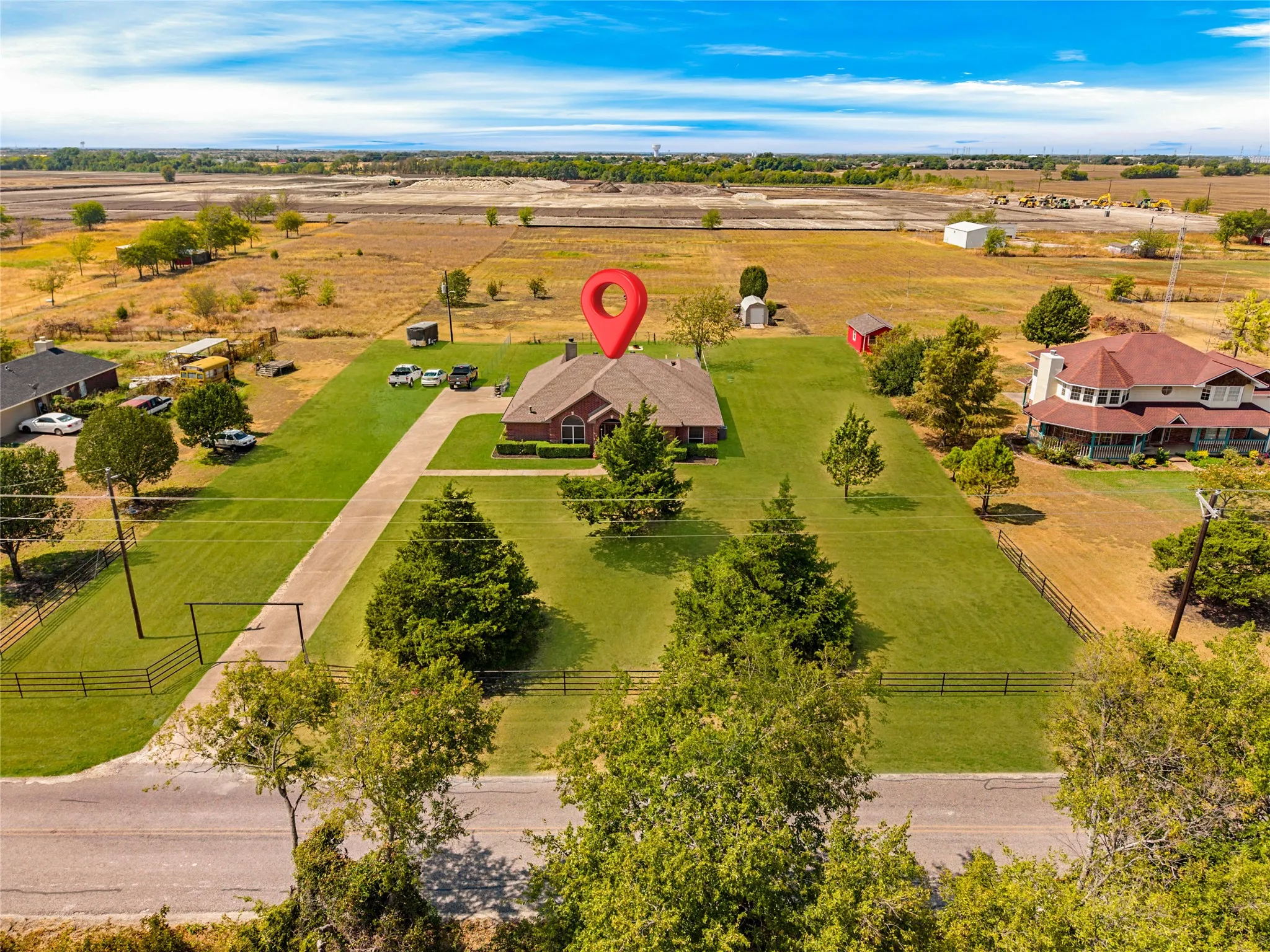 Single-story brick exterior, extensive green lawn, concrete driveway, and mature landscaping