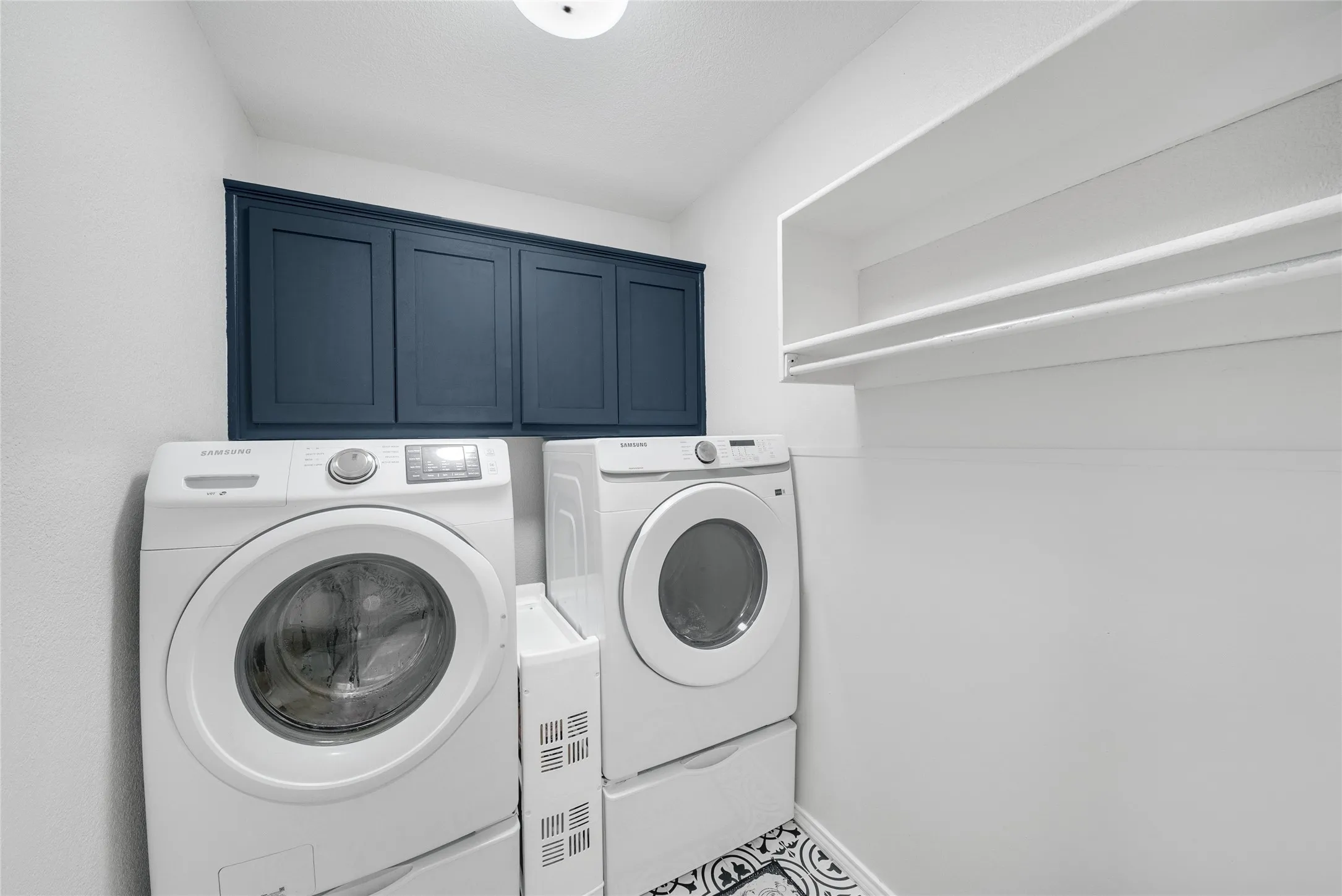 Built-in upper cabinetry, overhead shelving, and patterned tile flooring
