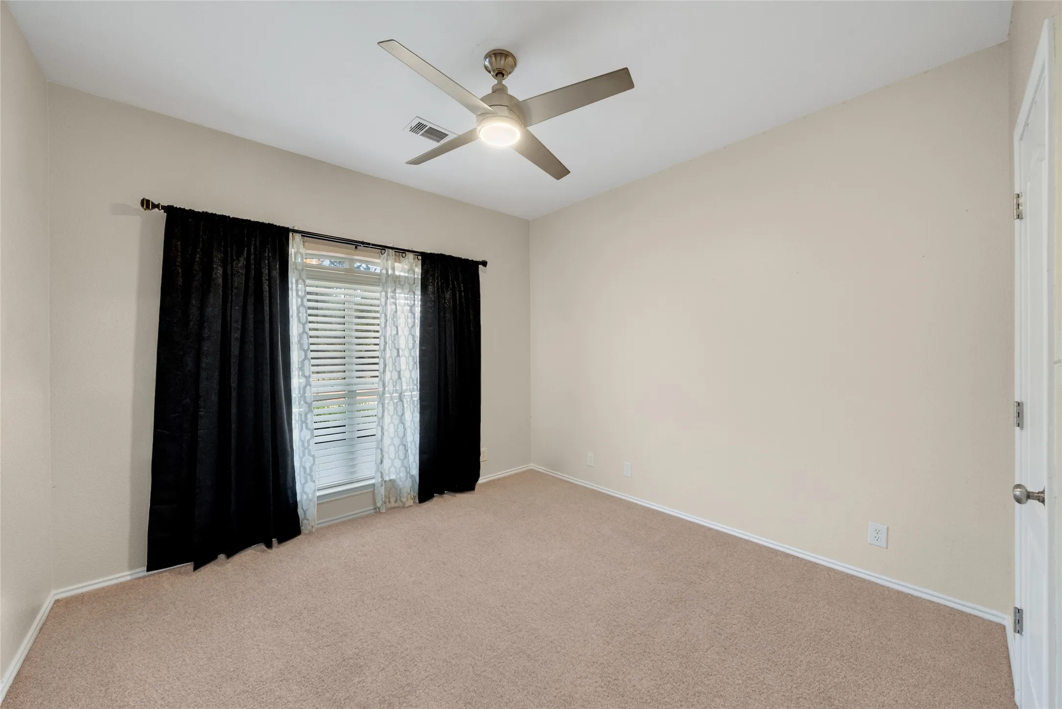 Carpeted flooring with a ceiling fan light fixture and a window with blinds