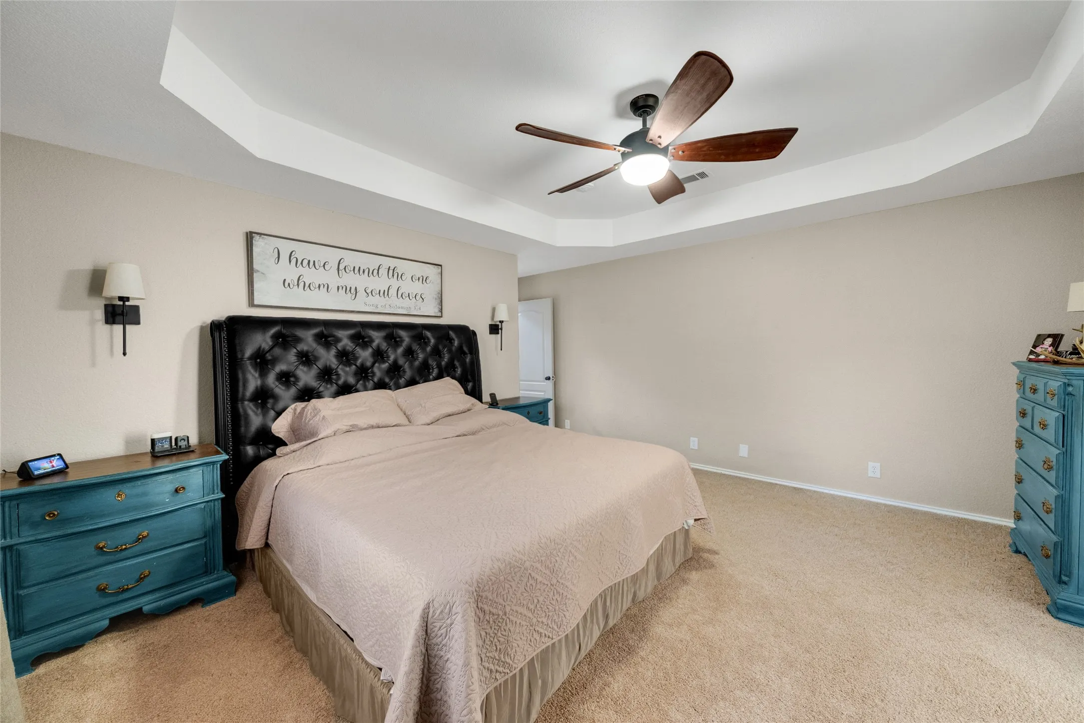 Tray ceiling with a ceiling fan light fixture, recessed wall sconces, and carpeting