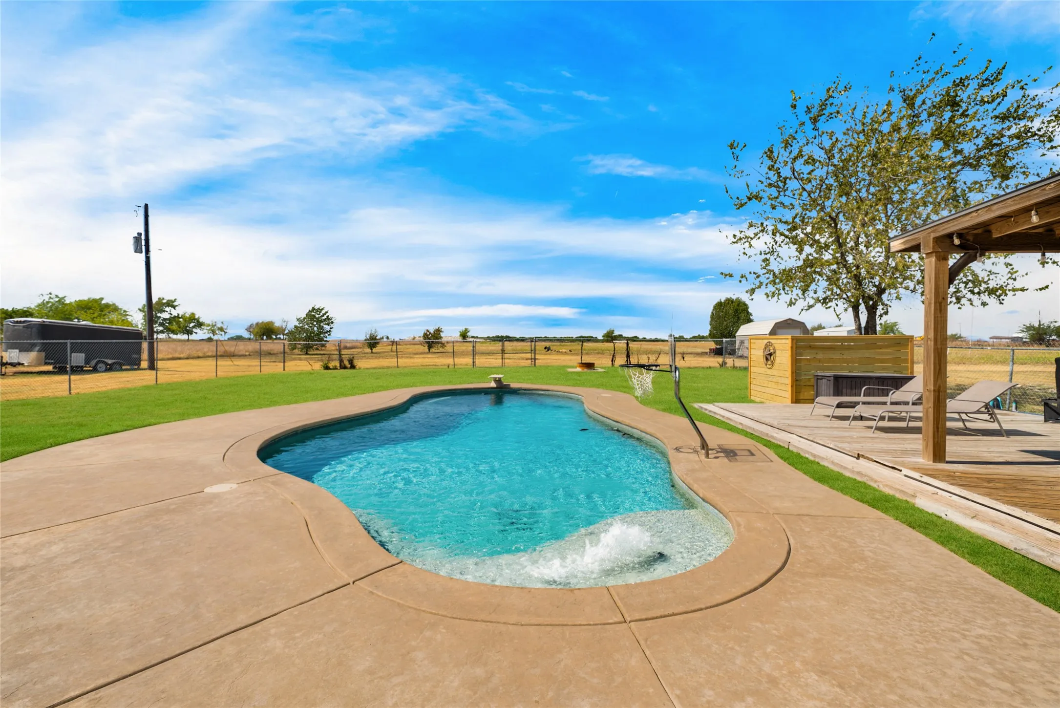 Freeform swimming pool with integrated spa, concrete decking, wood deck, and pergola