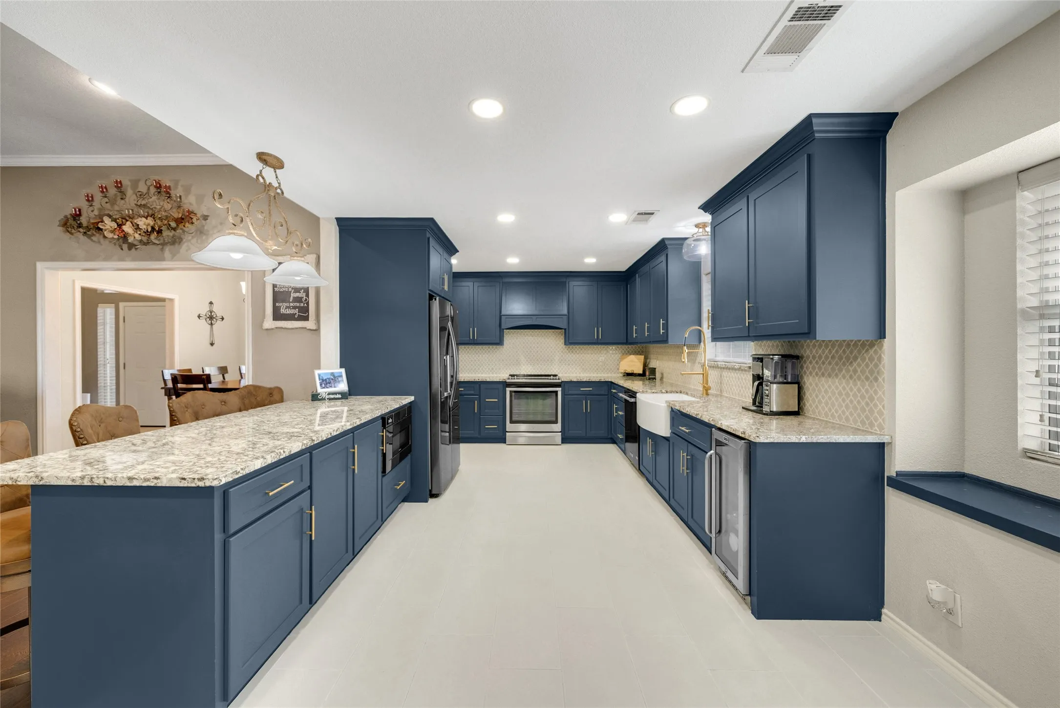 Kitchen featuring blue cabinetry, light-colored countertops, stainless steel appliances, a farmhouse-style sink, and recessed lighting