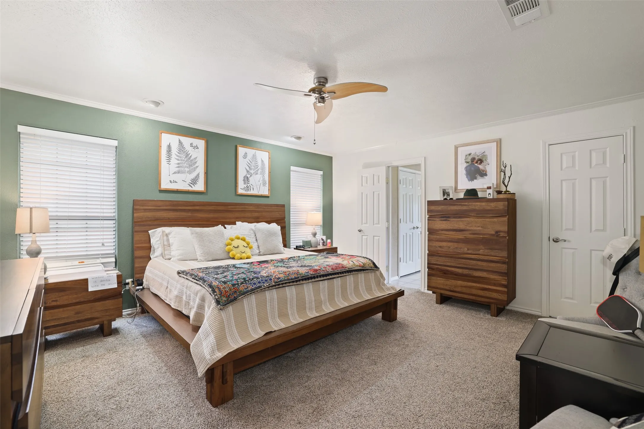 Spacious bedroom featuring carpet flooring, ceiling fan, and multiple windows with blinds