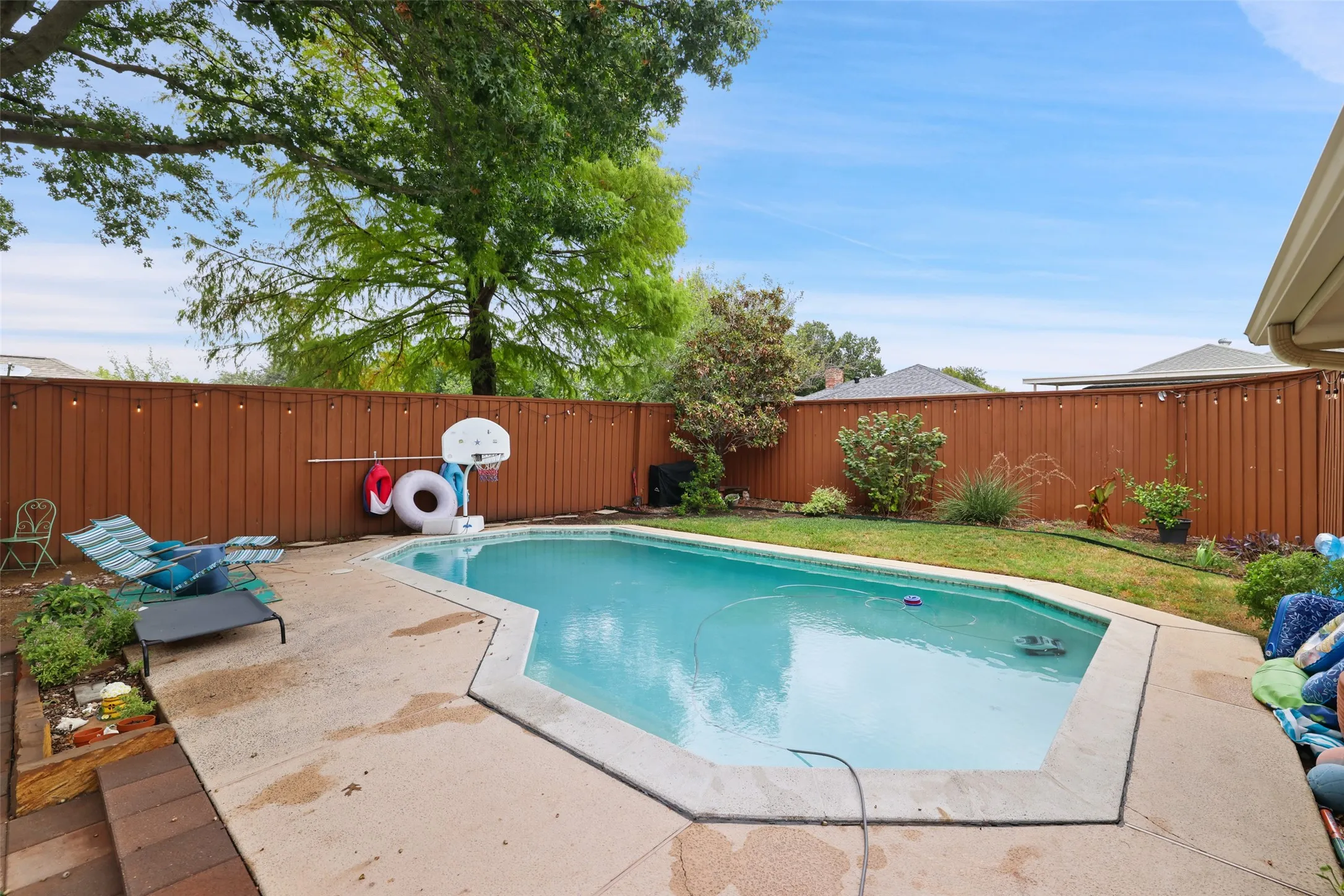Swimming pool with concrete decking, surrounded by a wood privacy fence
