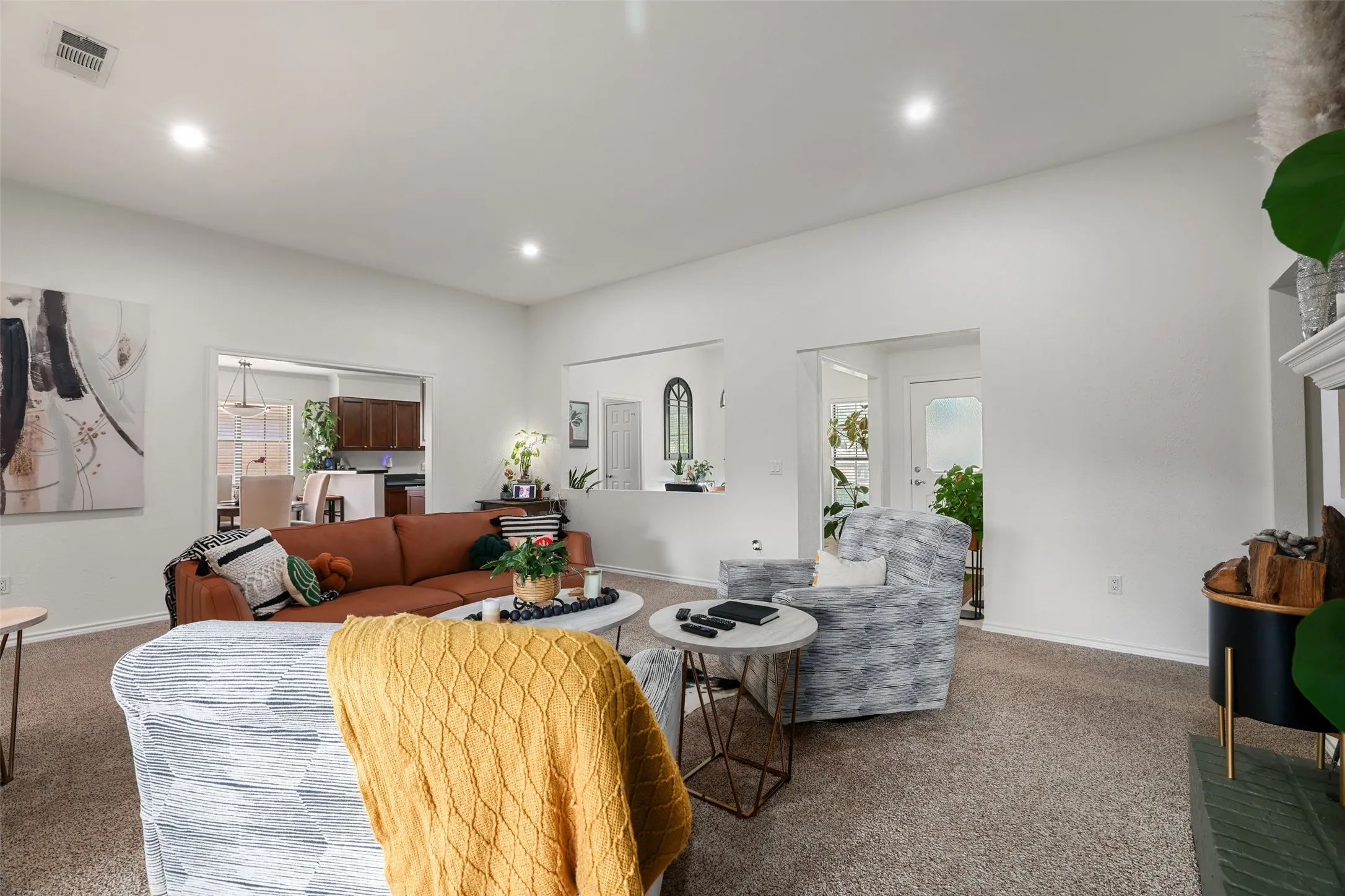 Recessed lighting illuminates a spacious living area featuring carpeted flooring and white walls