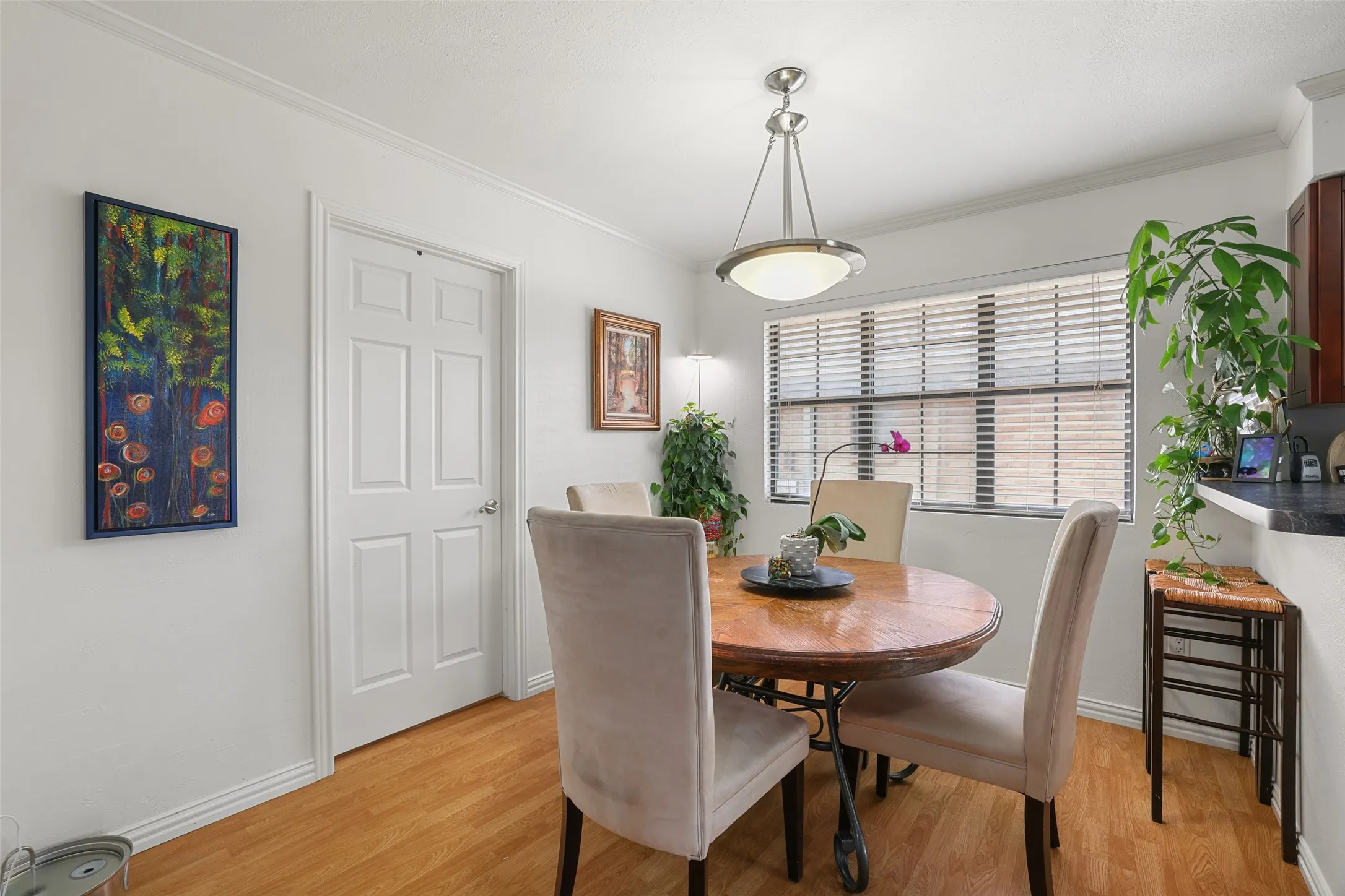 Wood-finish flooring with white baseboards, a six-panel door, and crown molding