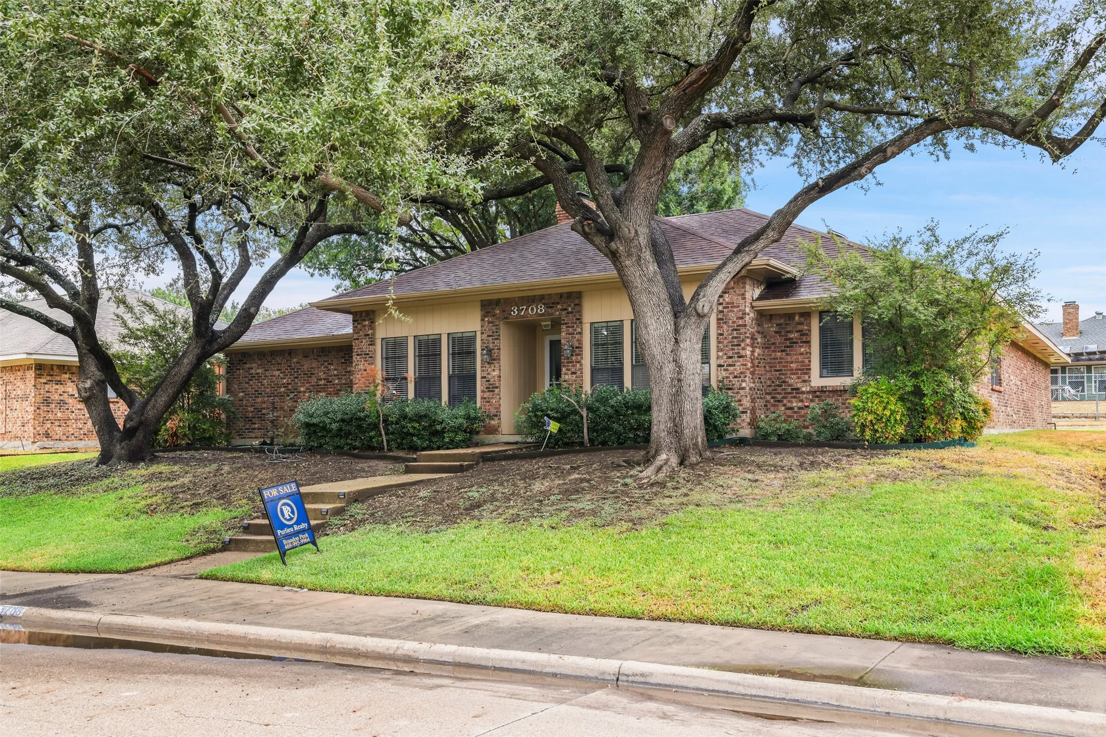 Brick exterior with a gabled roof and mature trees providing natural shade