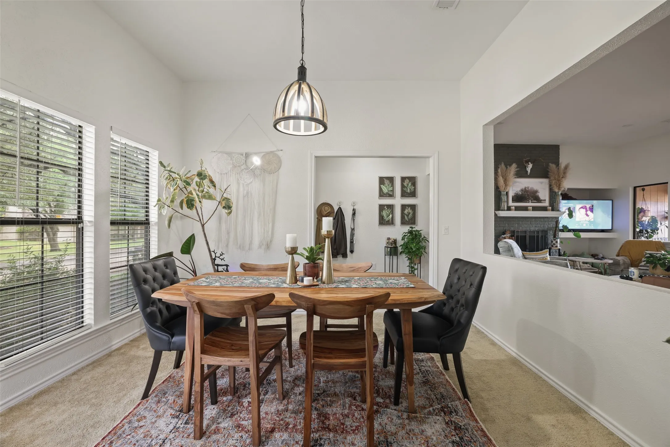 Vaulted ceiling with a contemporary pendant light fixture, dual windows, and an open pass-through to an adjacent living space