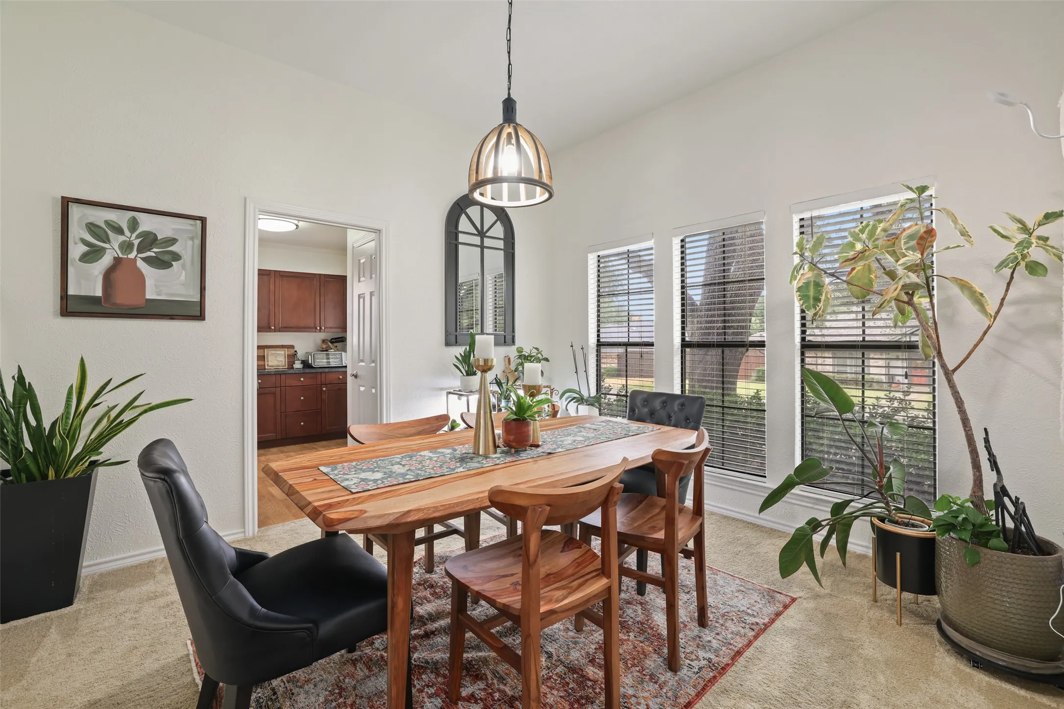Vaulted ceiling with an overhead light fixture, multiple windows with blinds, and light-toned wall finishes