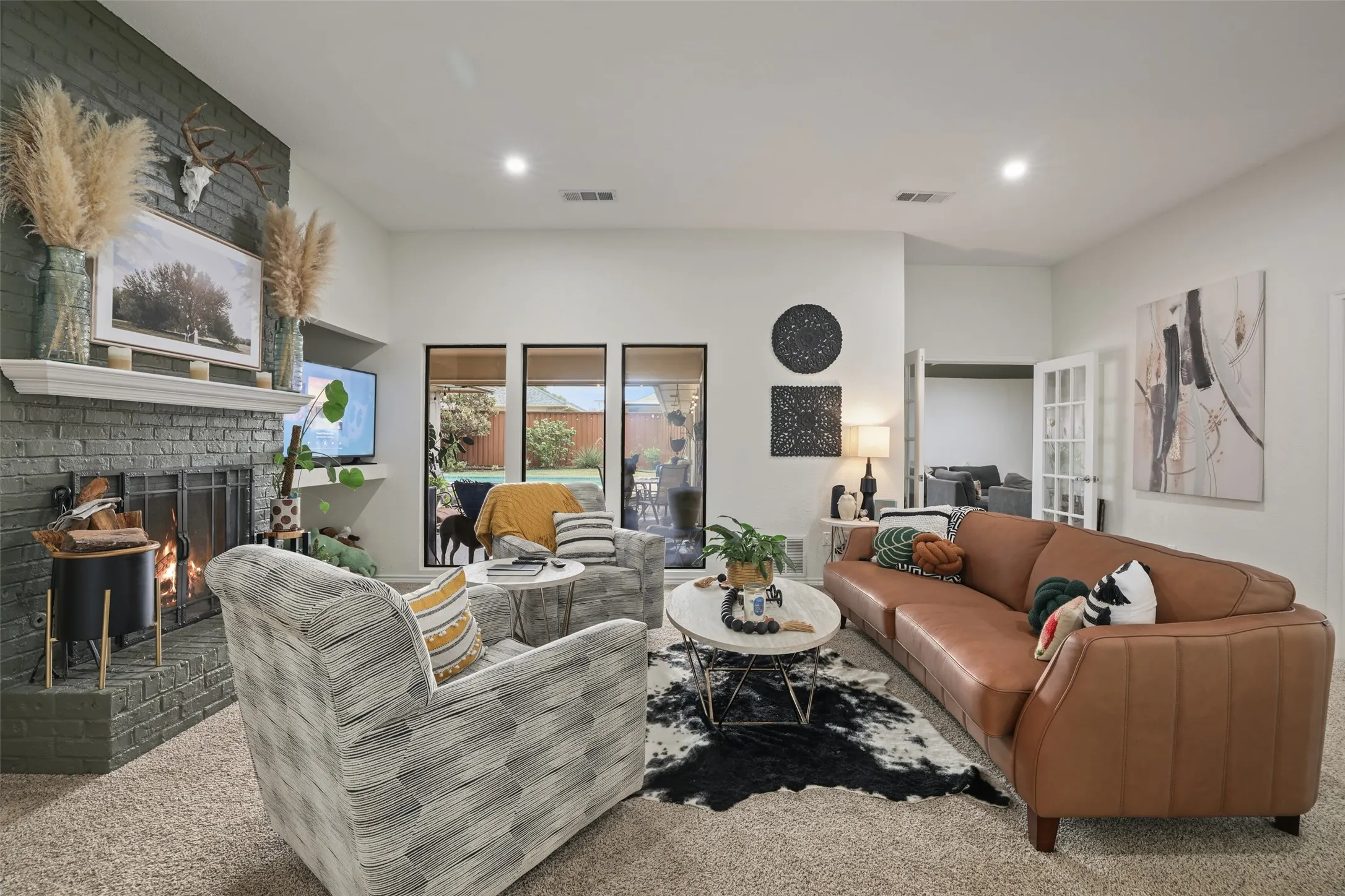 Spacious living area featuring a brick fireplace with a white mantel, recessed lighting, and multiple windows