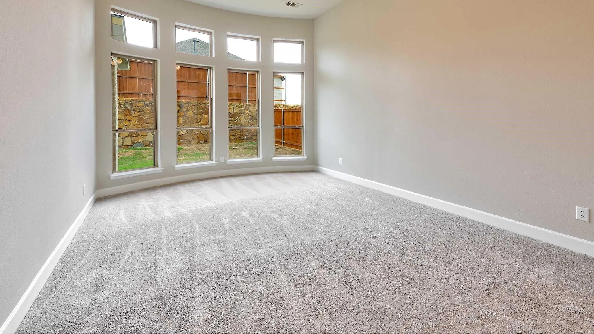 Curved wall with five tall windows, light gray carpet, and neutral painted walls