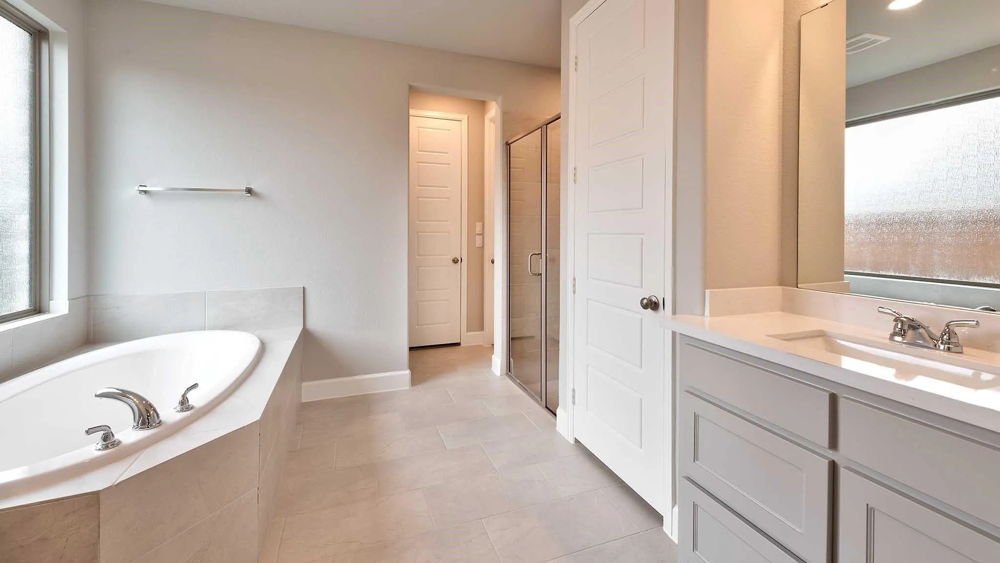 Soaking tub with a tiled surround, dual-sink vanity with white countertop, and a glass-enclosed shower