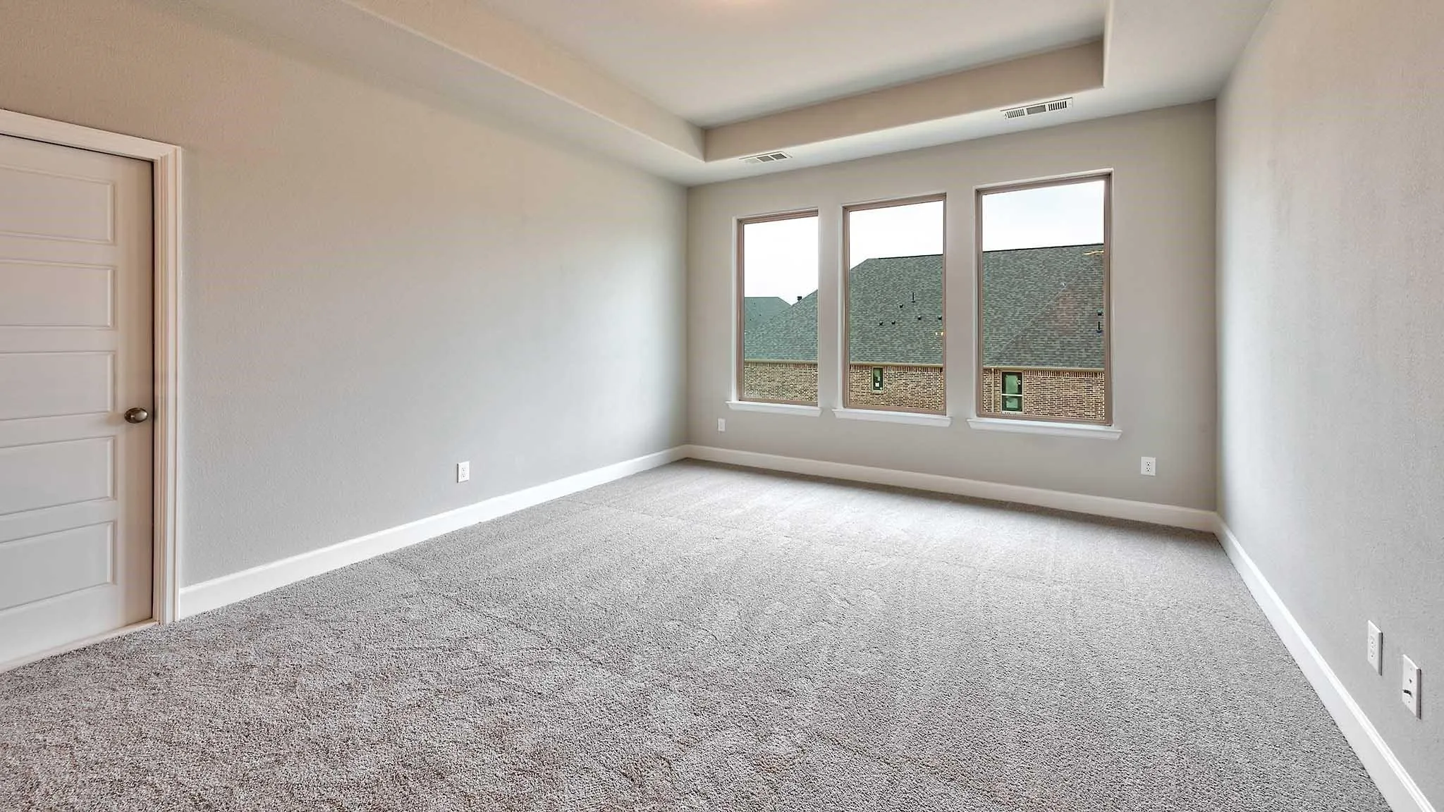 Tray ceiling, recessed lighting, neutral wall paint, gray carpeting, and modern paneled door