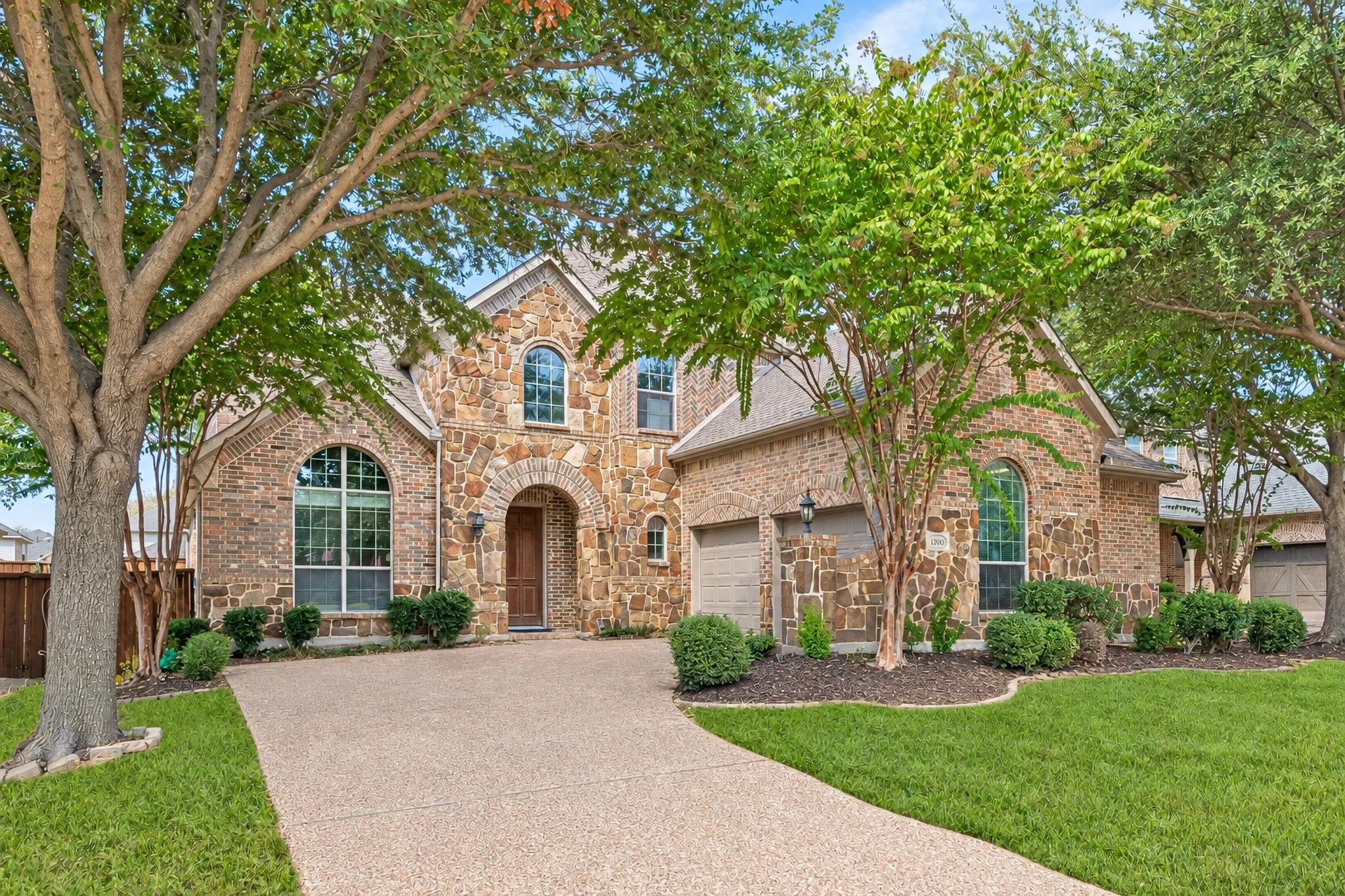 Gorgeous Stone And Brick Twin Creeks Home!  Slight Angle Photo To Showcase The Garage. Grass Has Been Virtually Greened and Patched Where Missing Grass Is Due To Shade Trees.