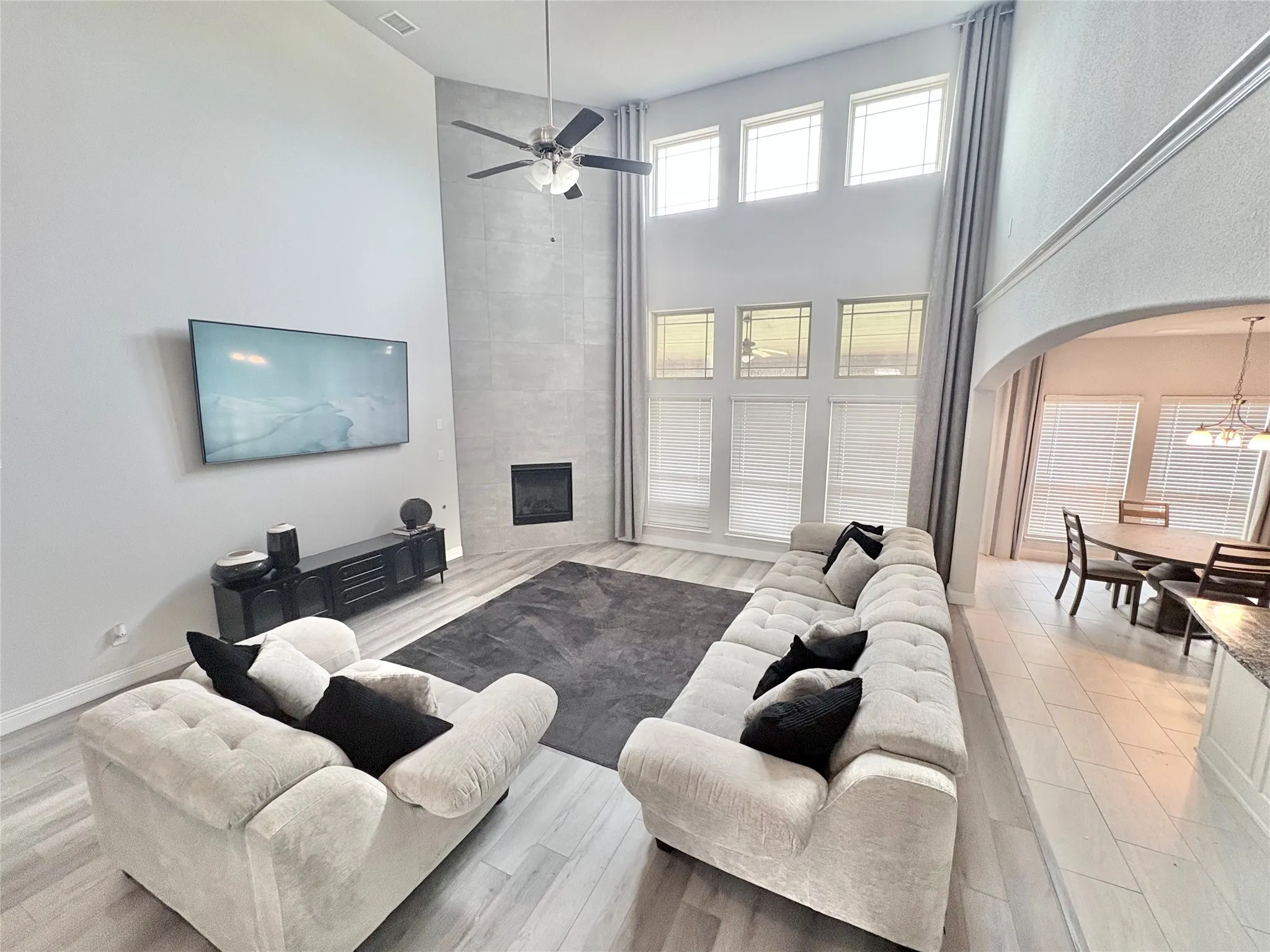 Two-story ceiling, integrated fireplace, multi-pane windows, ceiling fan, and wood-finish flooring