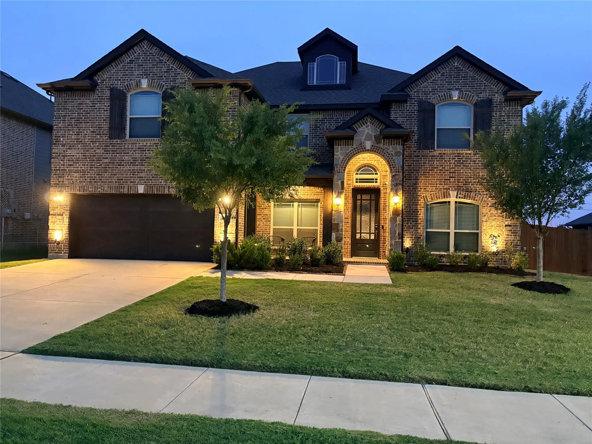 Brick facade with stone accents, arched entryway, and dark garage door