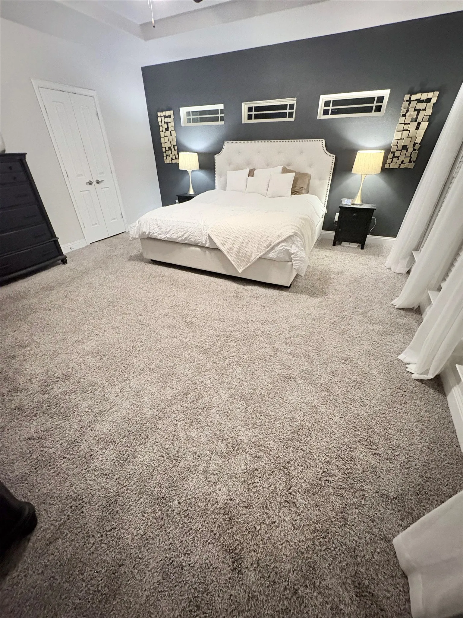 Tray ceiling with recessed lighting, plush carpet flooring, and a contrasting accent wall