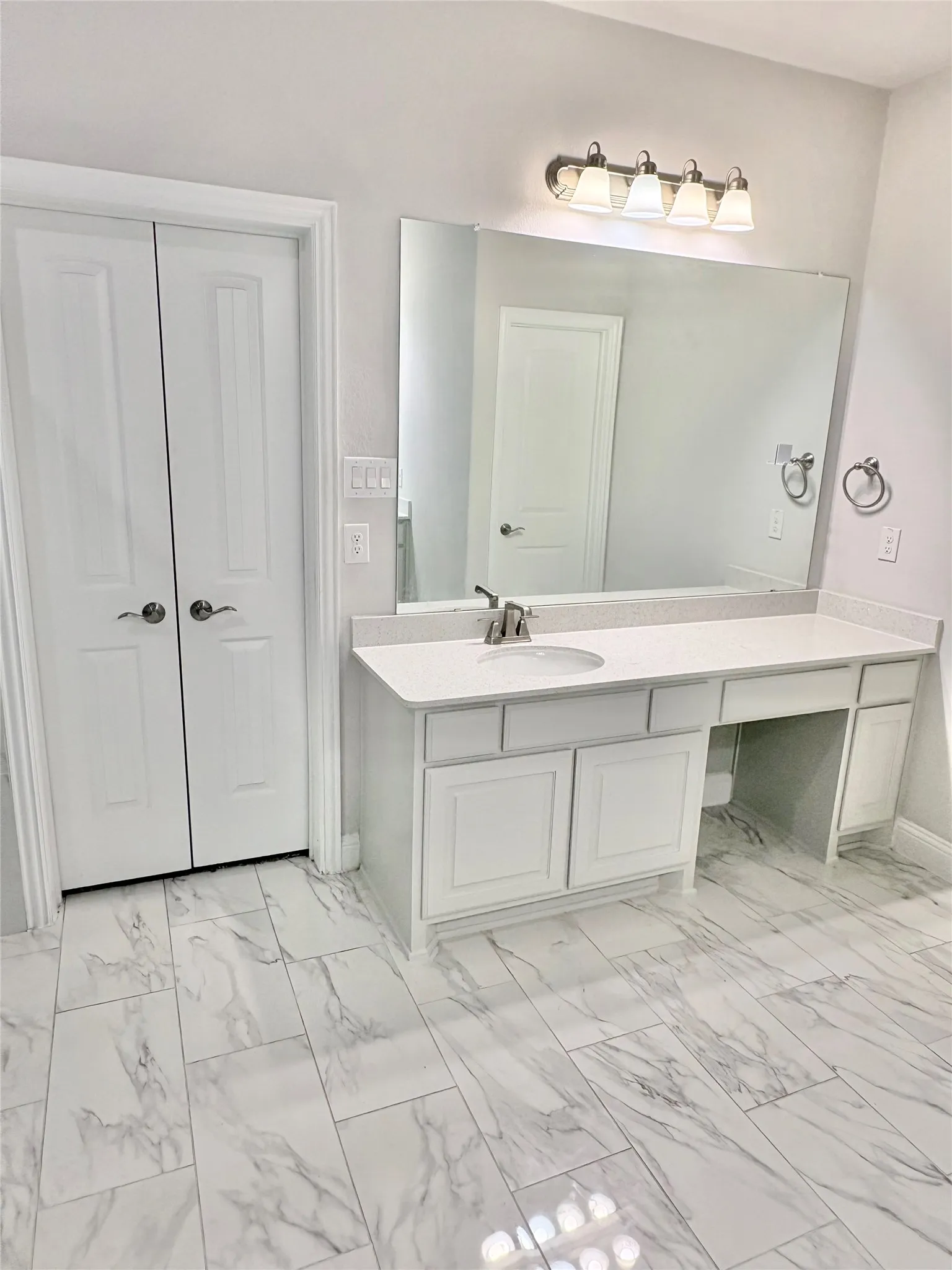 White shaker-style vanity with an integrated sink, polished chrome faucet, and expansive counter space