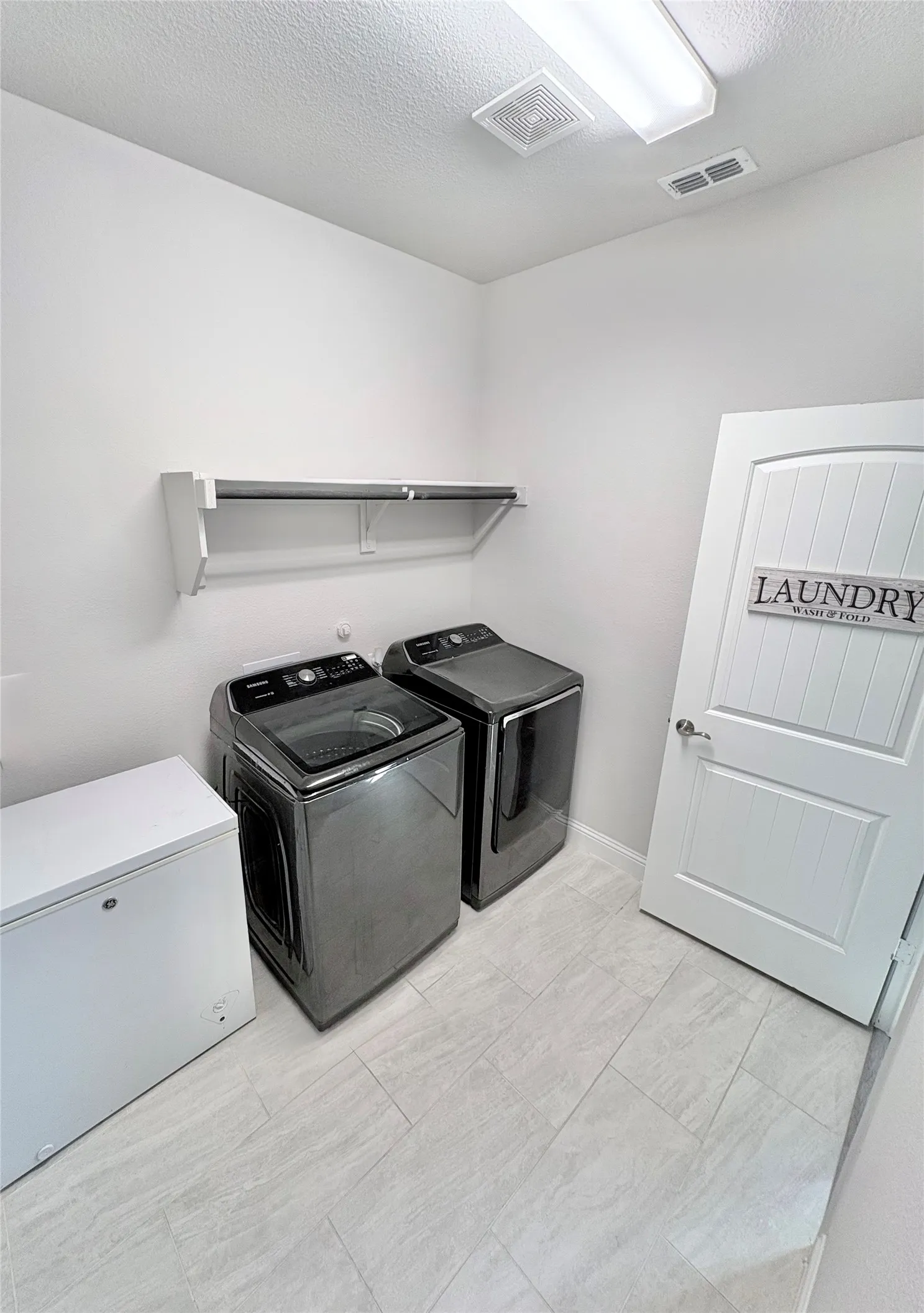 Light-toned tile flooring, overhead fluorescent lighting, and a wall-mounted shelving unit