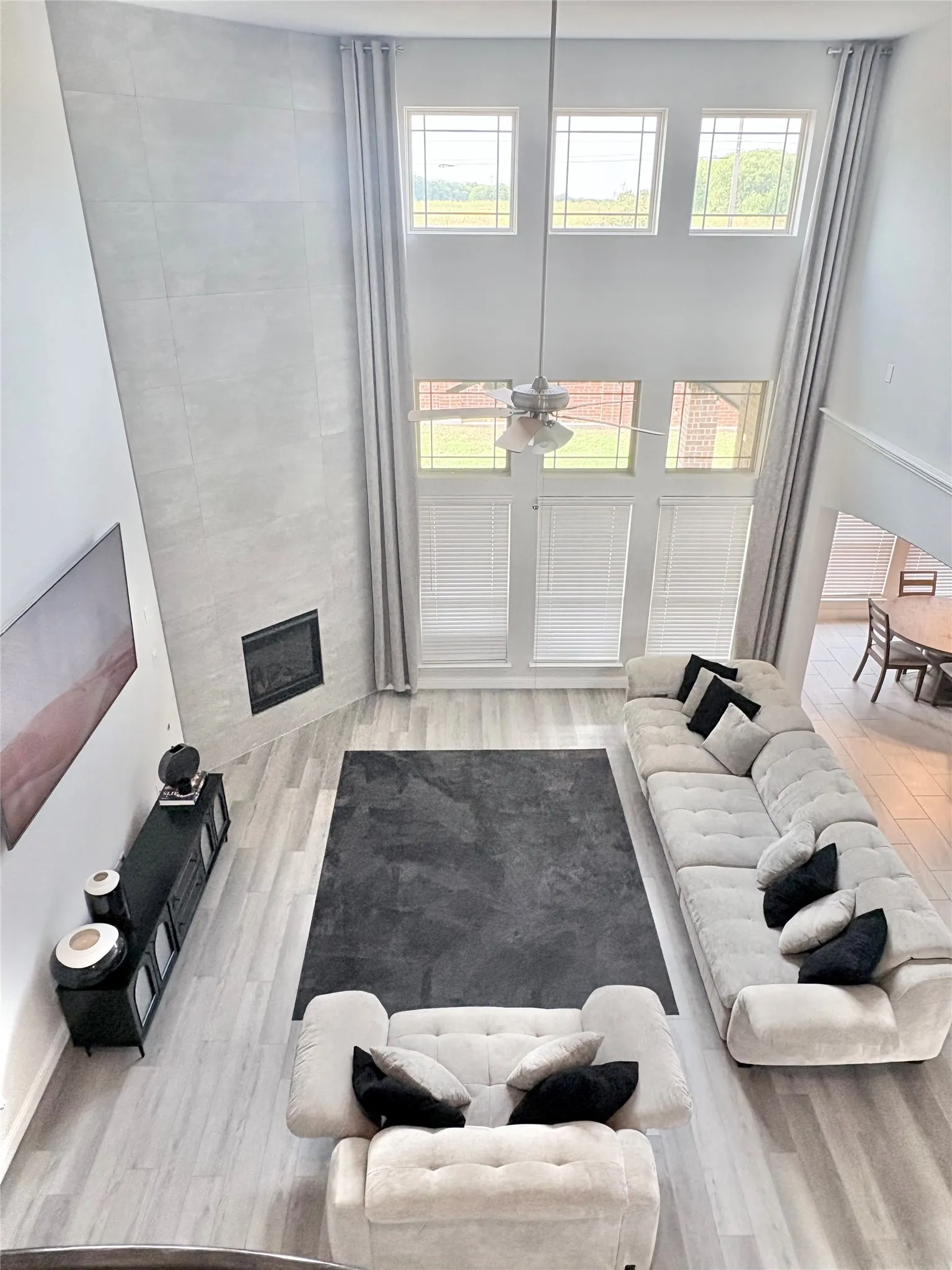 Vaulted ceiling living area featuring wood-finish flooring, a contemporary fireplace, and multiple windows