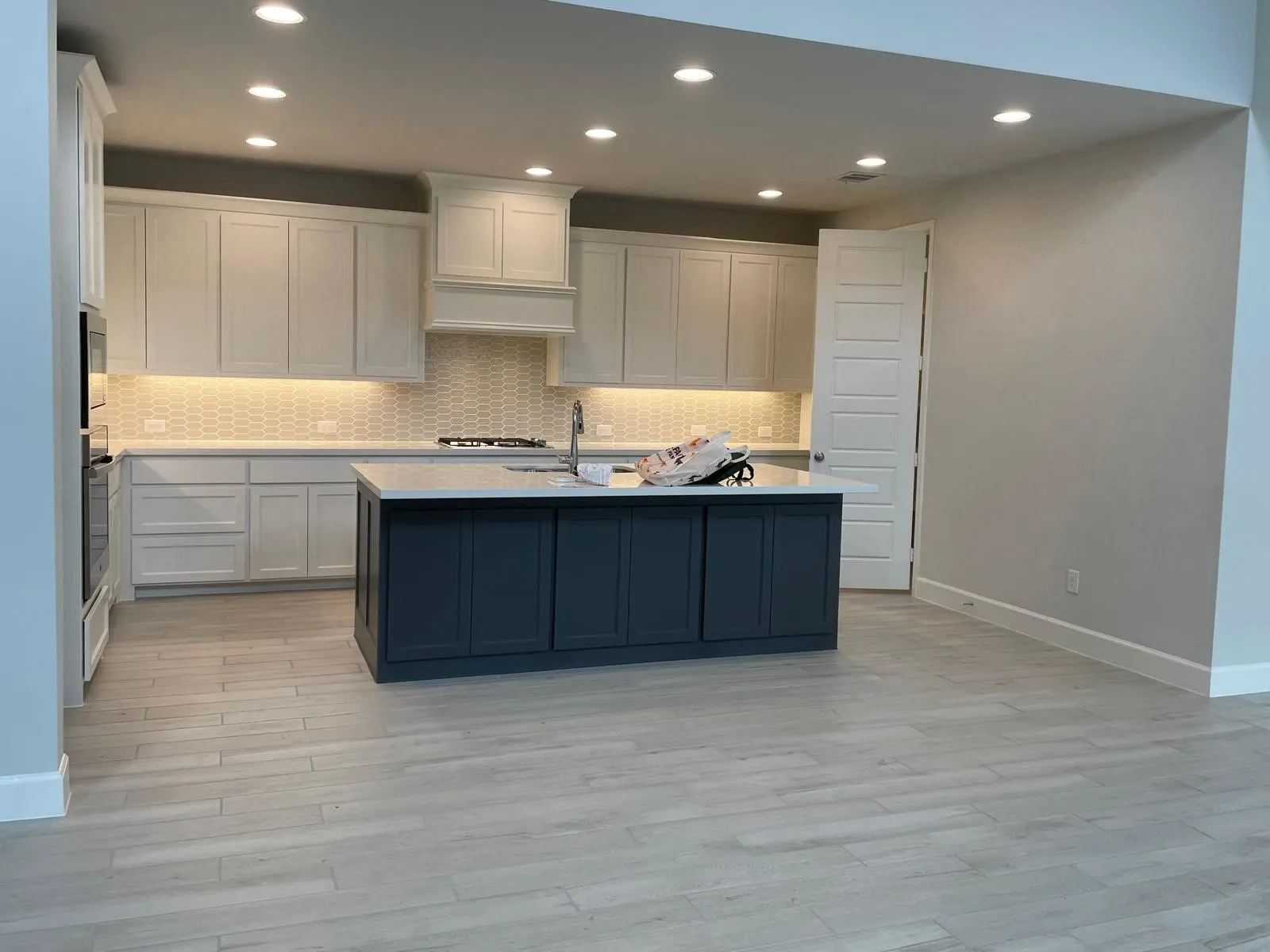 Kitchen with light hardwood / wood-style flooring, sink, white cabinets, and a kitchen island with sink
