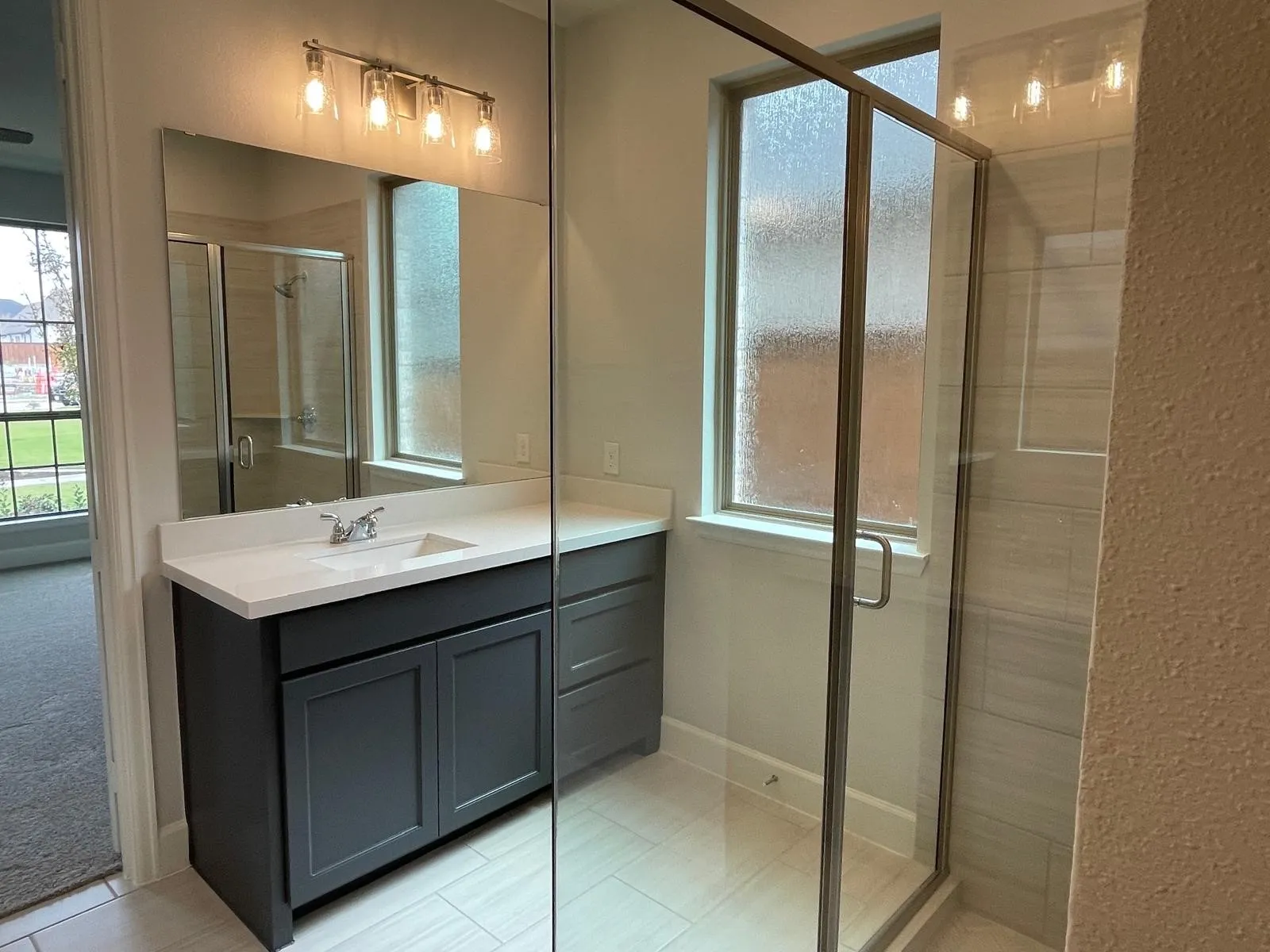 Bathroom featuring tile patterned flooring, a shower with door, and vanity