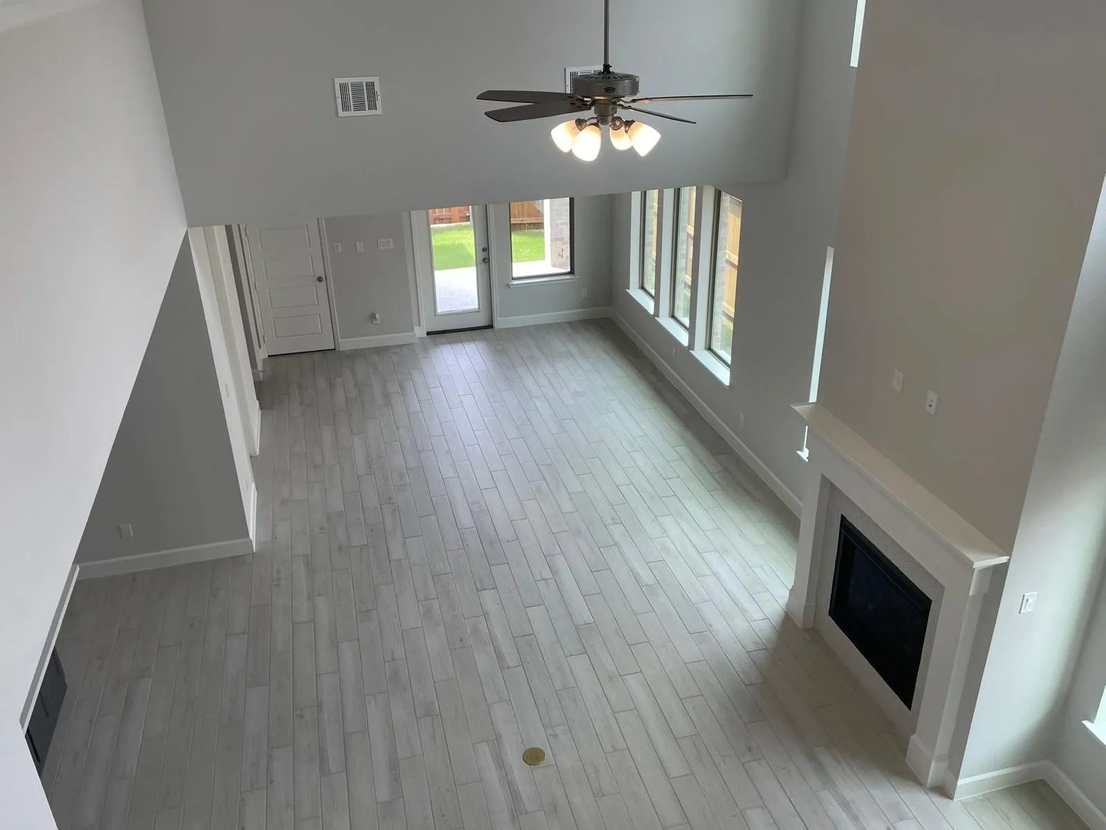 Unfurnished living room with light wood-type flooring, a high ceiling, and ceiling fan