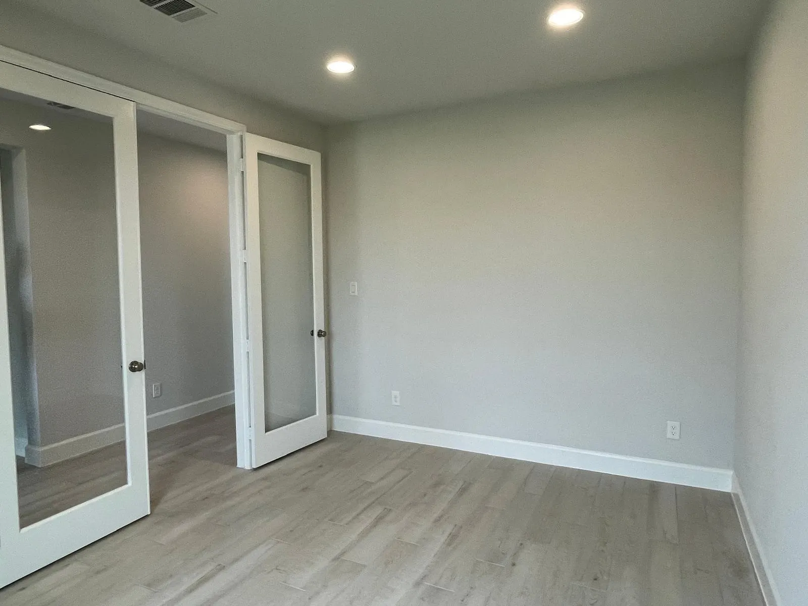 Unfurnished bedroom with french doors, light hardwood / wood-style flooring, and a closet