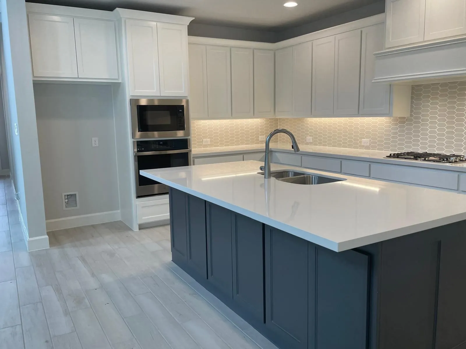 Kitchen featuring stainless steel appliances, light hardwood / wood-style floors, white cabinetry, sink, and a kitchen island with sink