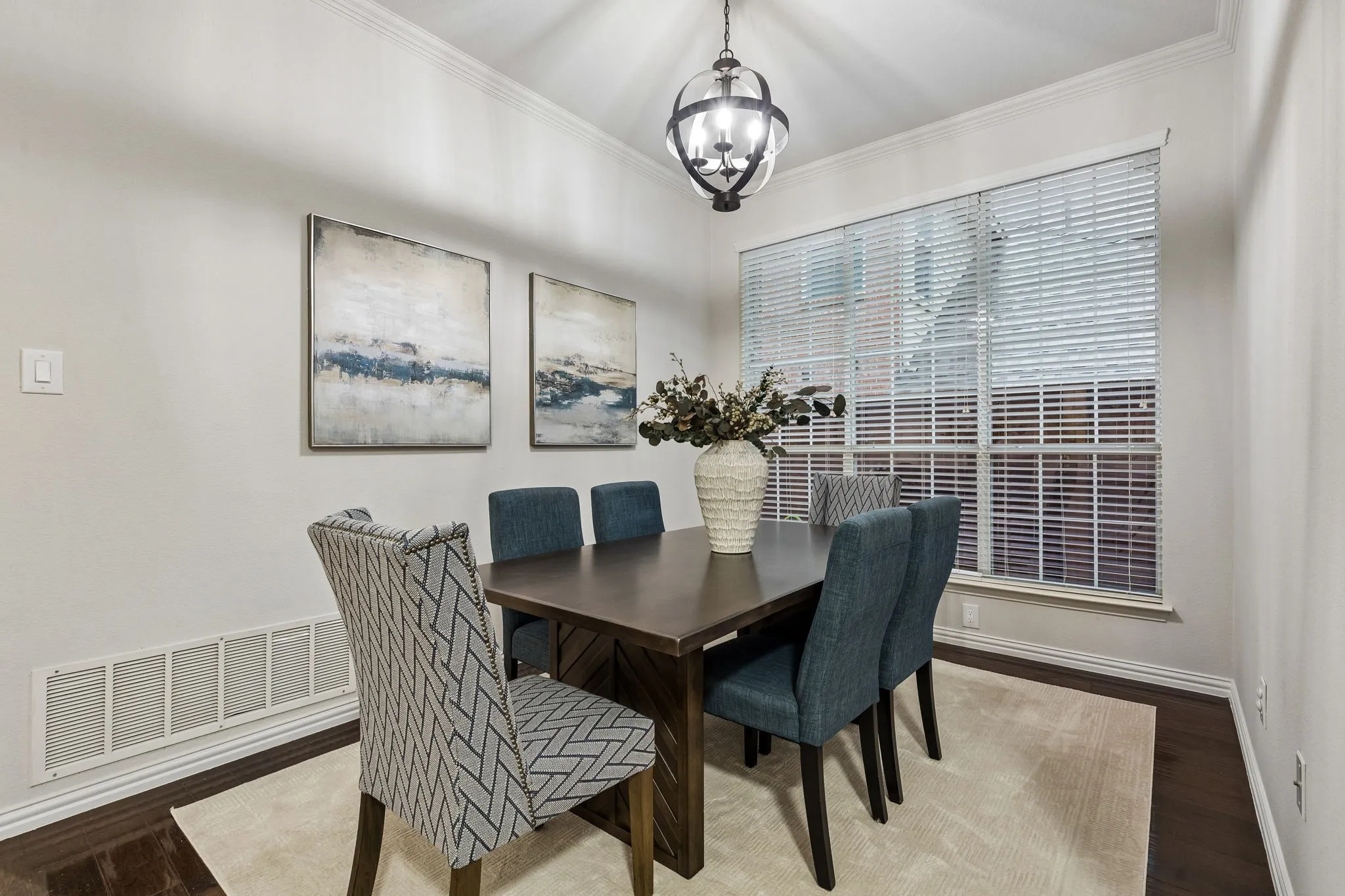 Hardwood-finish flooring with crown molding and a large window featuring blinds