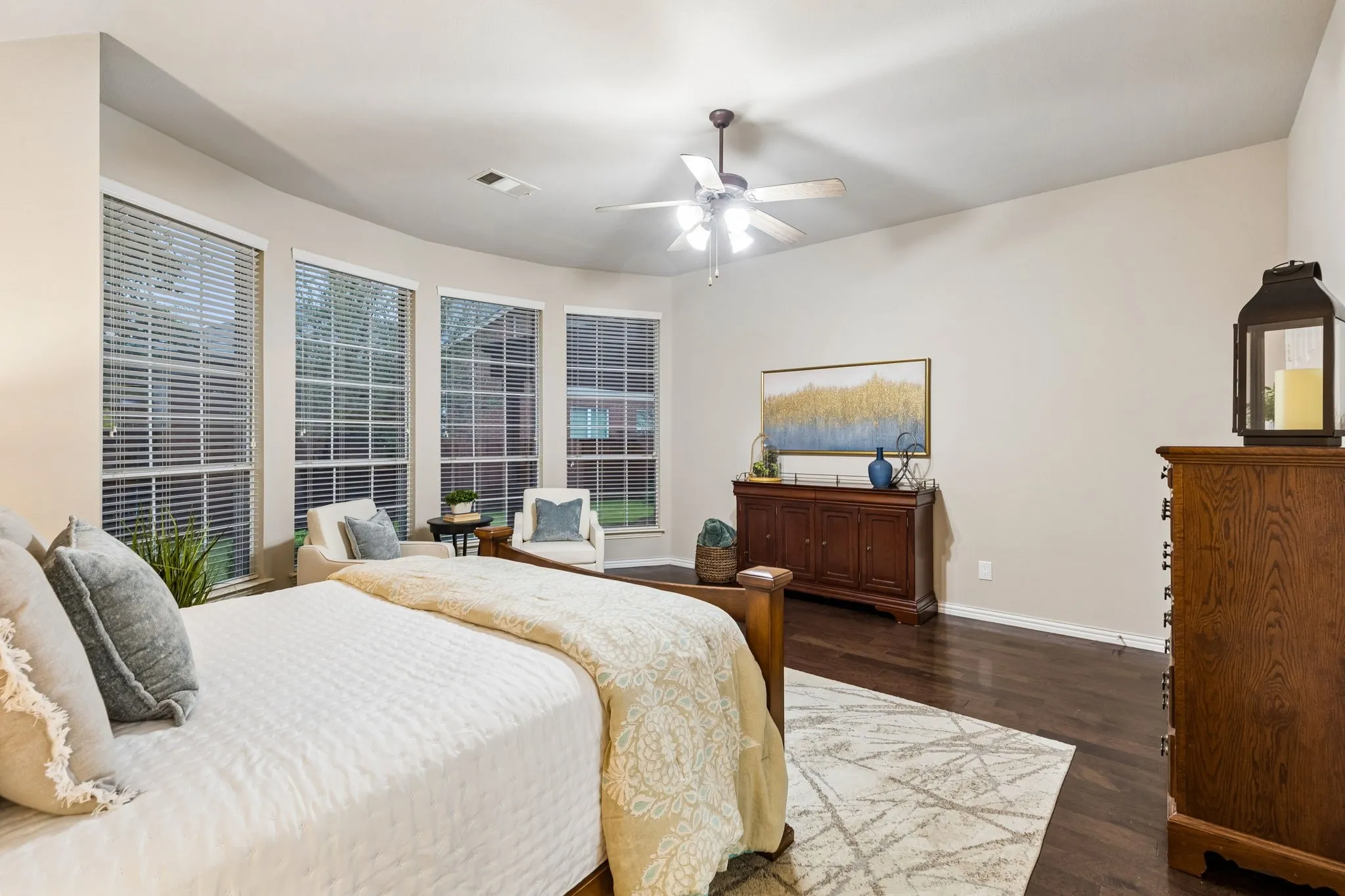 Hardwood-style flooring, a curved wall of multiple windows with blinds, and a ceiling fan