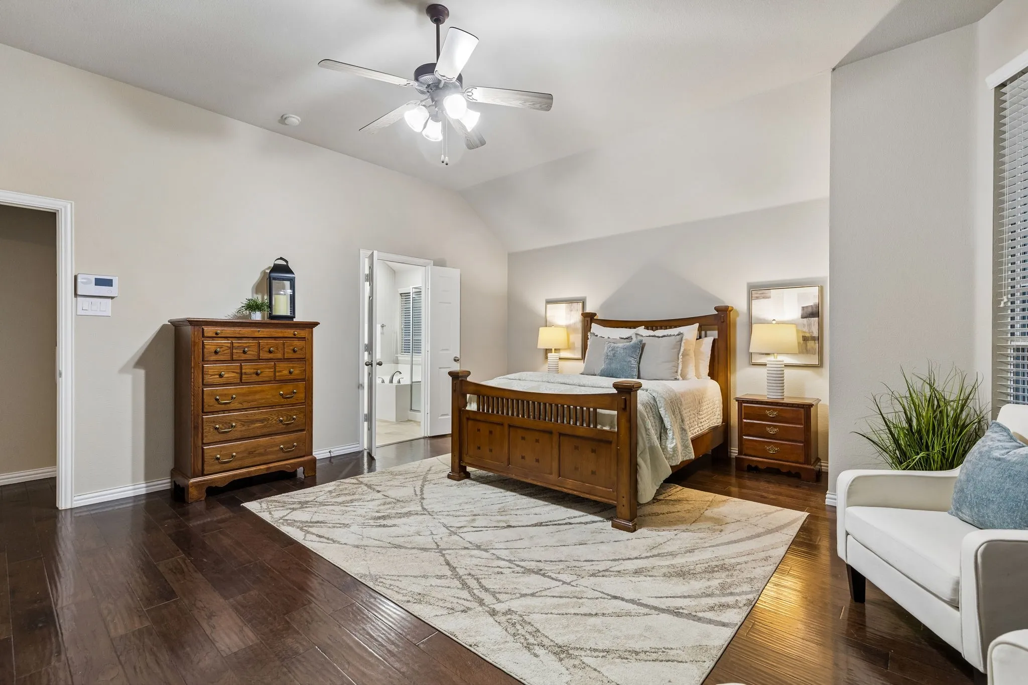 Vaulted ceiling with a ceiling fan, dark wood-finish flooring, and white wall paint