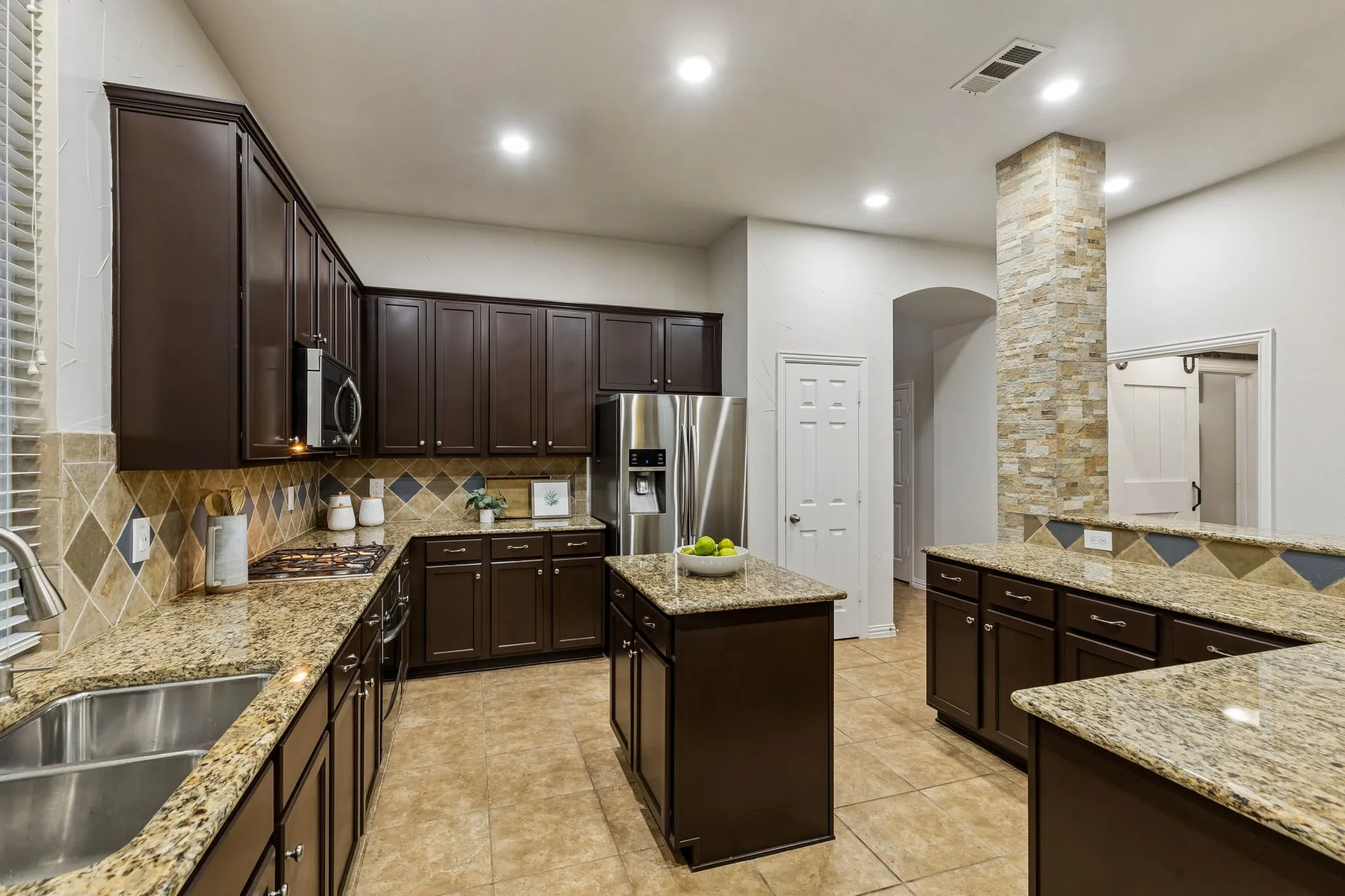 Stainless steel appliances, recessed lighting, tile flooring, granite countertops, and a stone-clad architectural column