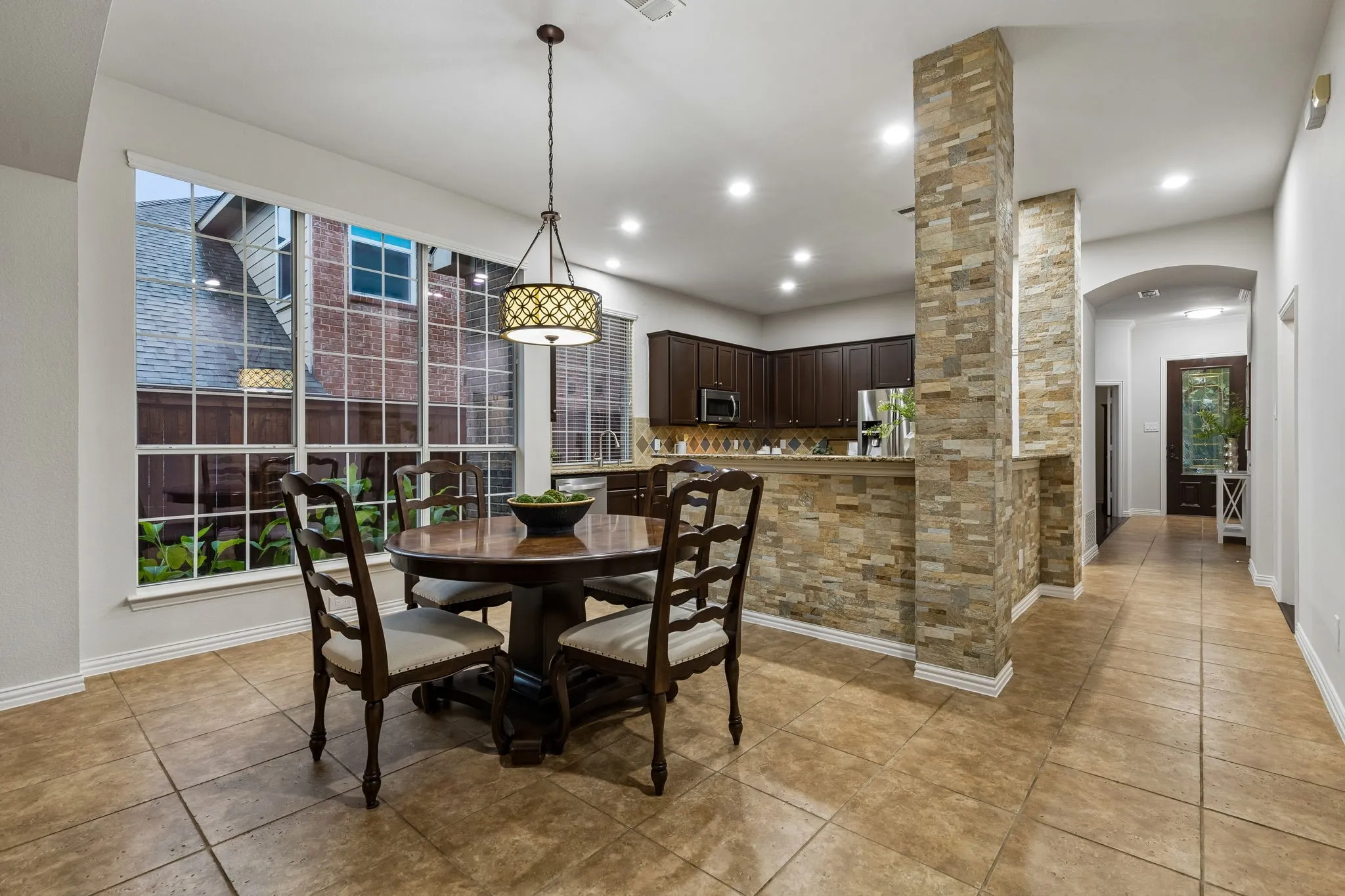 Tile flooring, recessed lighting, expansive window with grid panes, textured stone accent wall, and built-in cabinetry