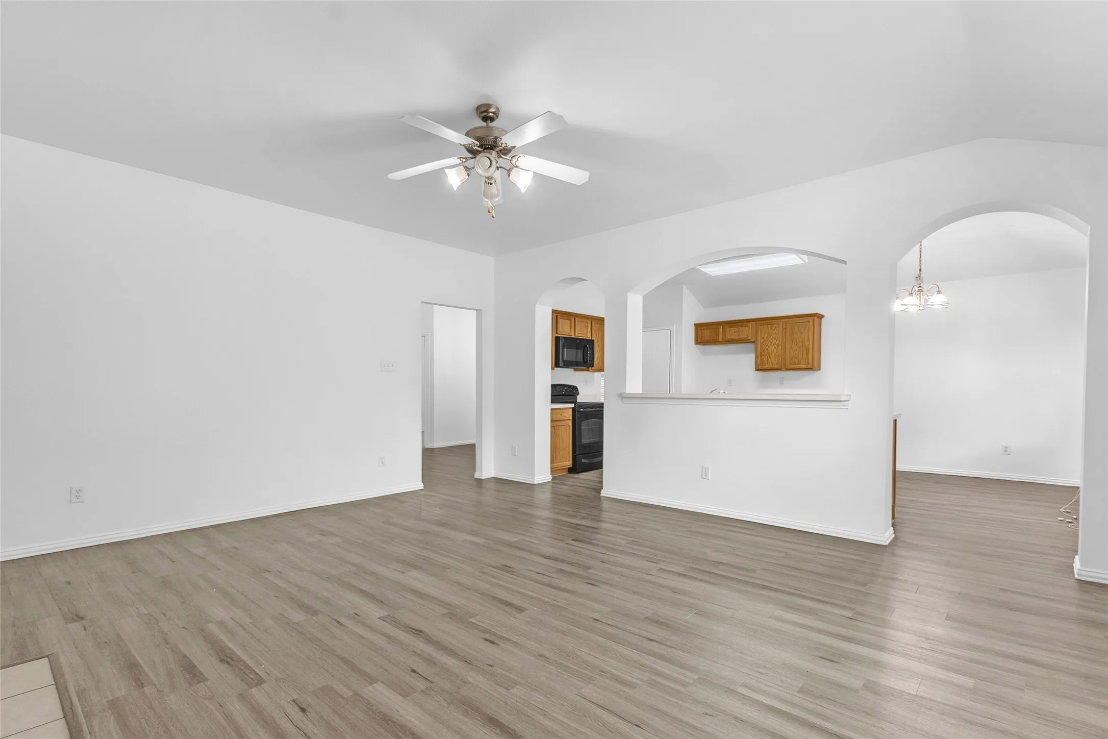 Living room open to the kitchen through arched openings, with a breakfast bar and eating area