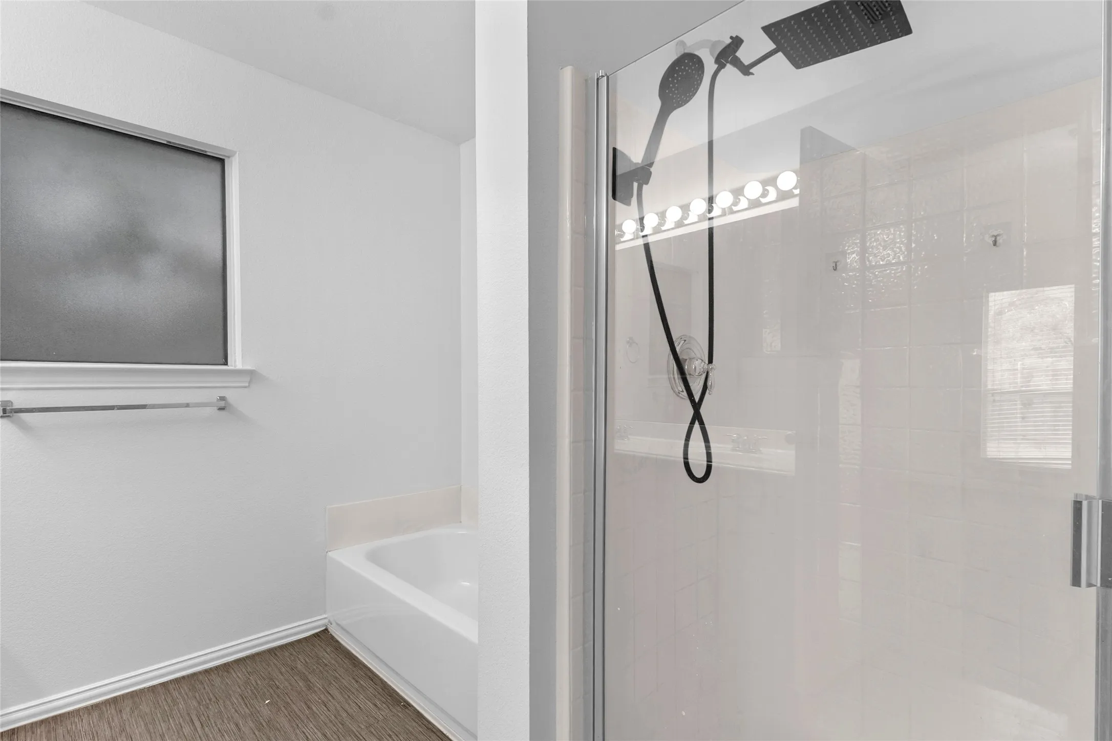 Primary bath with a separate tub and a glass-enclosed shower with rain showerhead and handheld spray