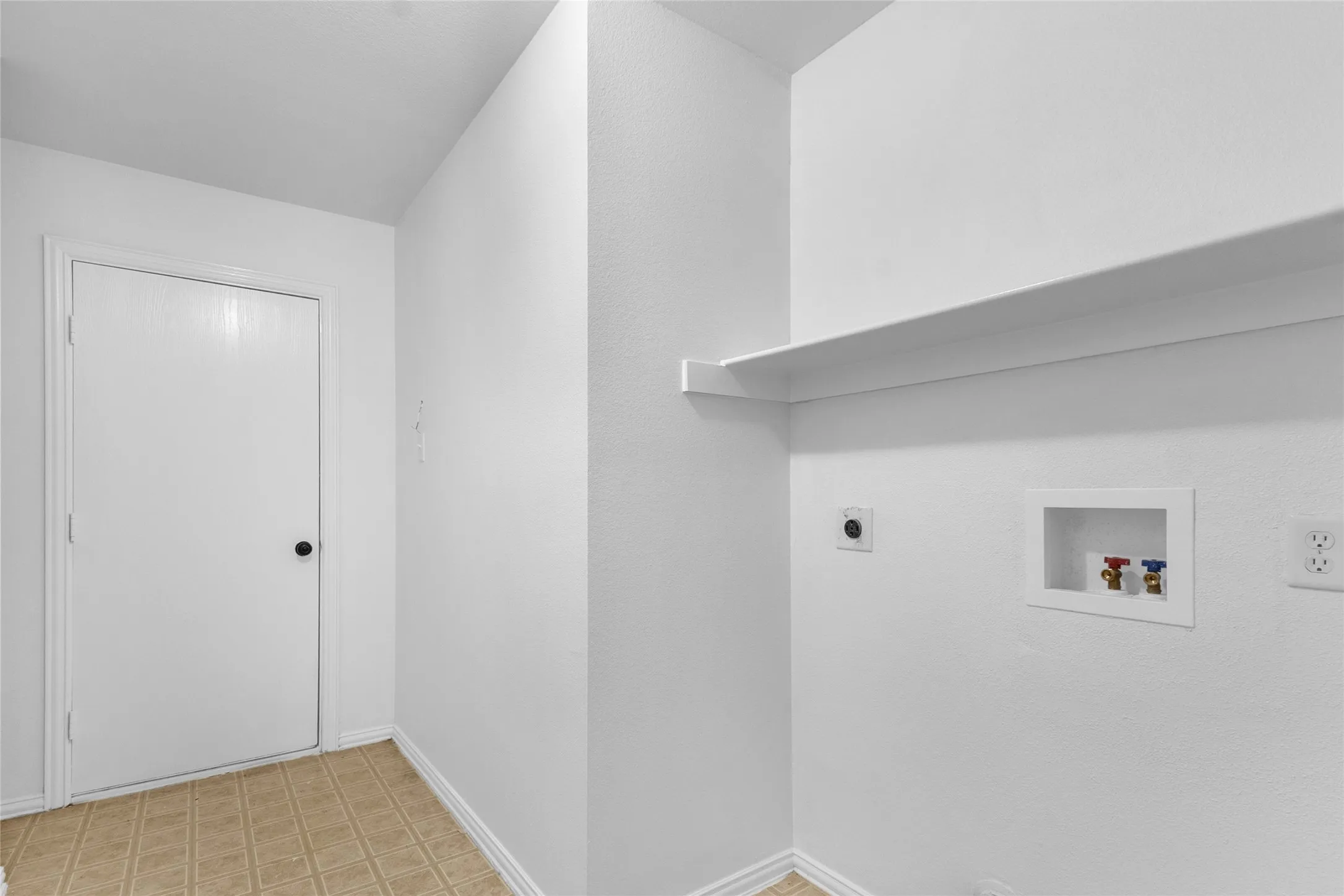 Laundry room with washer and dryer connections, a wall shelf, and tile-look flooring