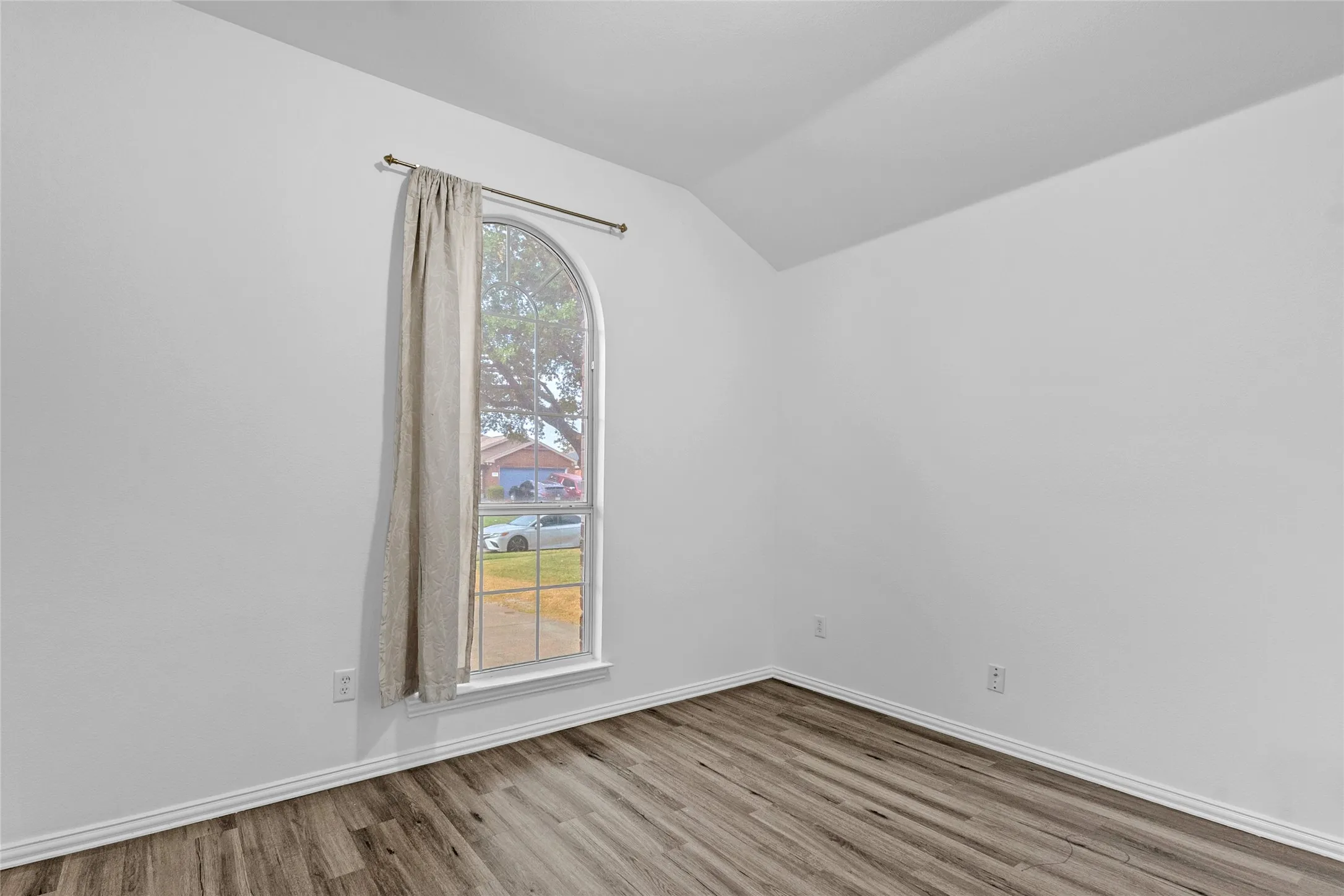 Front office with vaulted ceiling, tall arched window, and wood-look floors in this River Ridge home