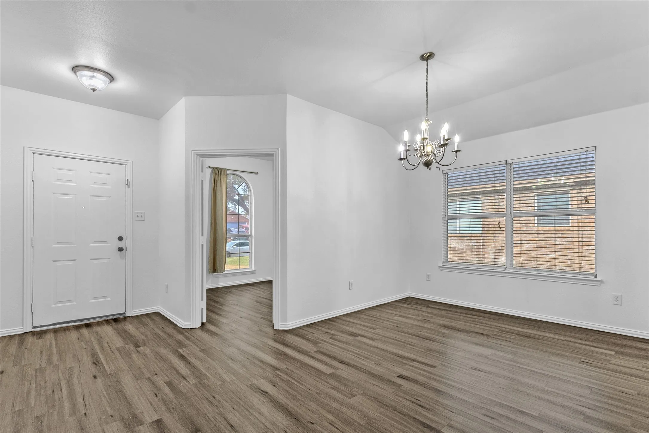 Dining room with chandelier and wood-look floors, open to the foyer and front office in this Crandall home