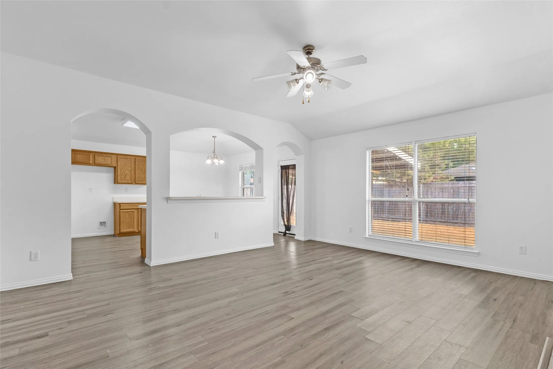 Living room with a large backyard window and arched openings to the kitchen and breakfast nook