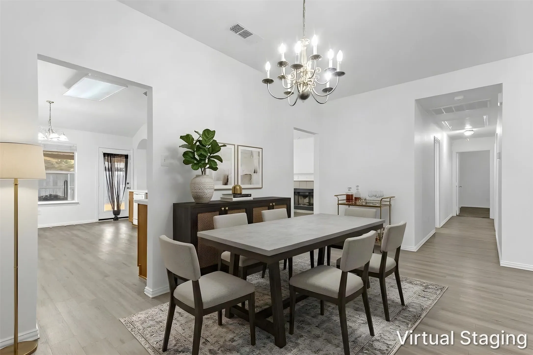 Virtually staged dining room with chandelier and wood-look floors, open to the kitchen and hall