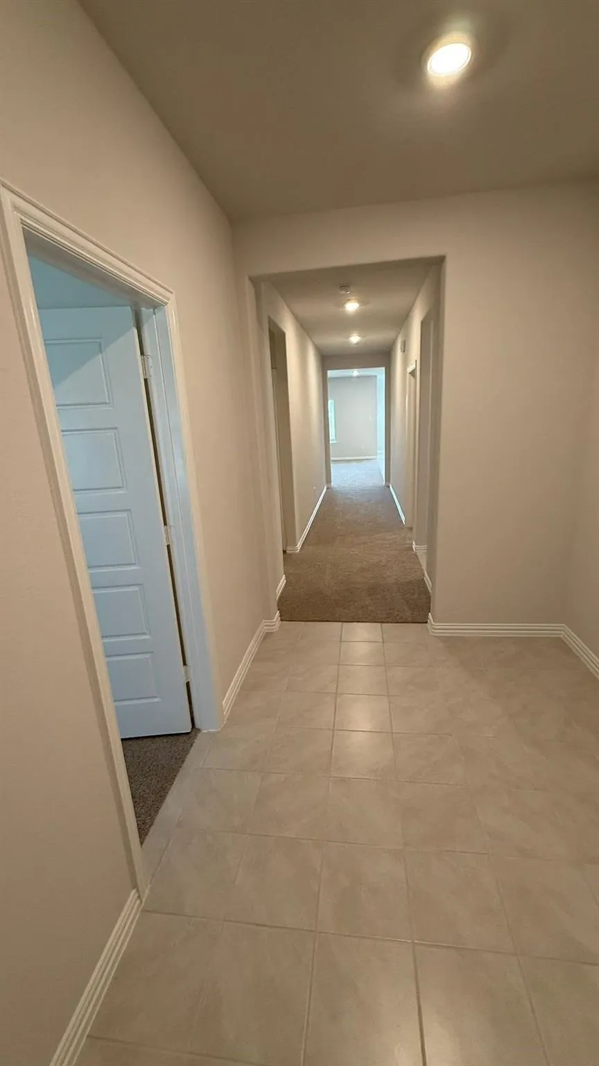 Hallway featuring recessed lighting, light-toned wall paint, and two flooring types: tile and carpet
