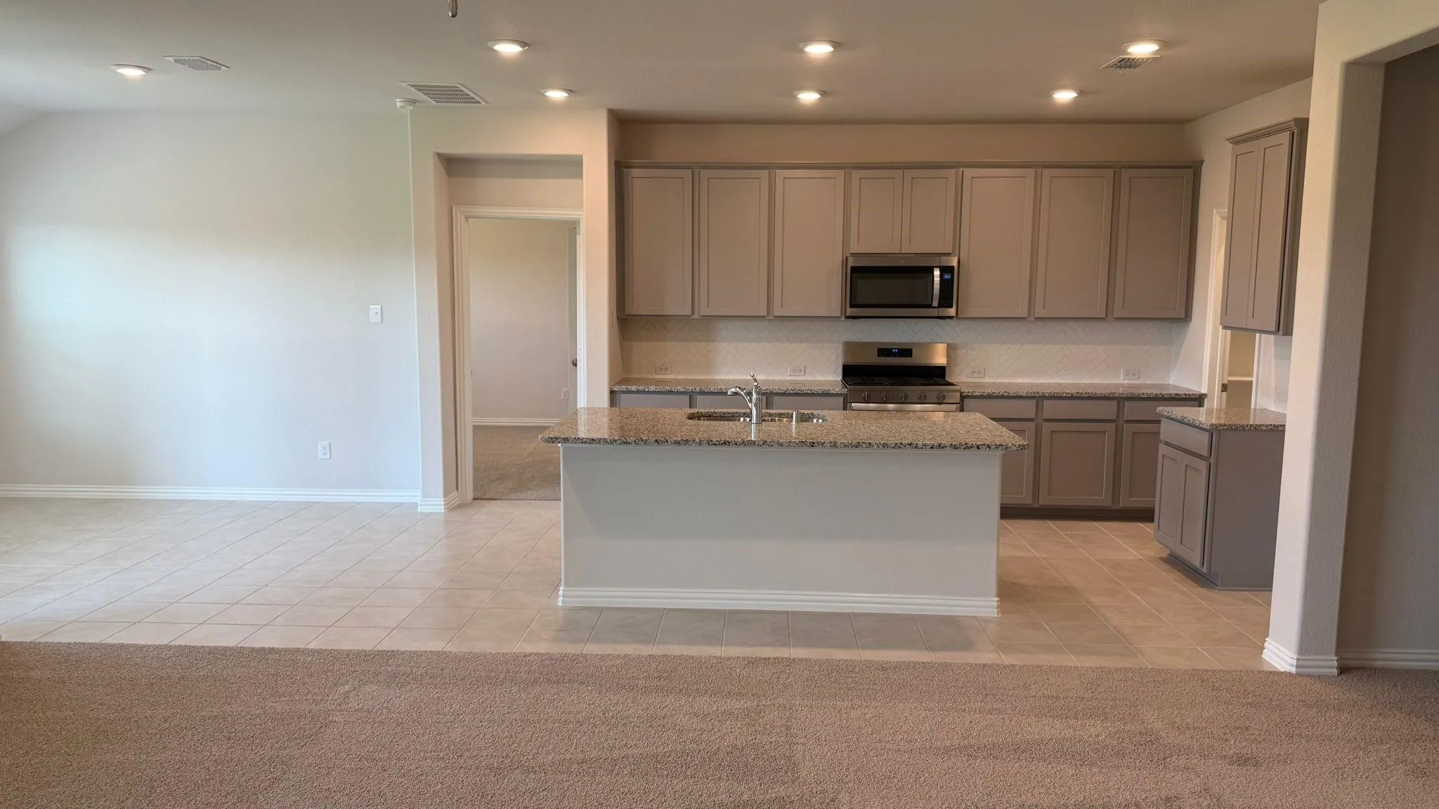 Kitchen featuring recessed lighting, extensive cabinetry, a central island with a sink, and stainless steel appliances